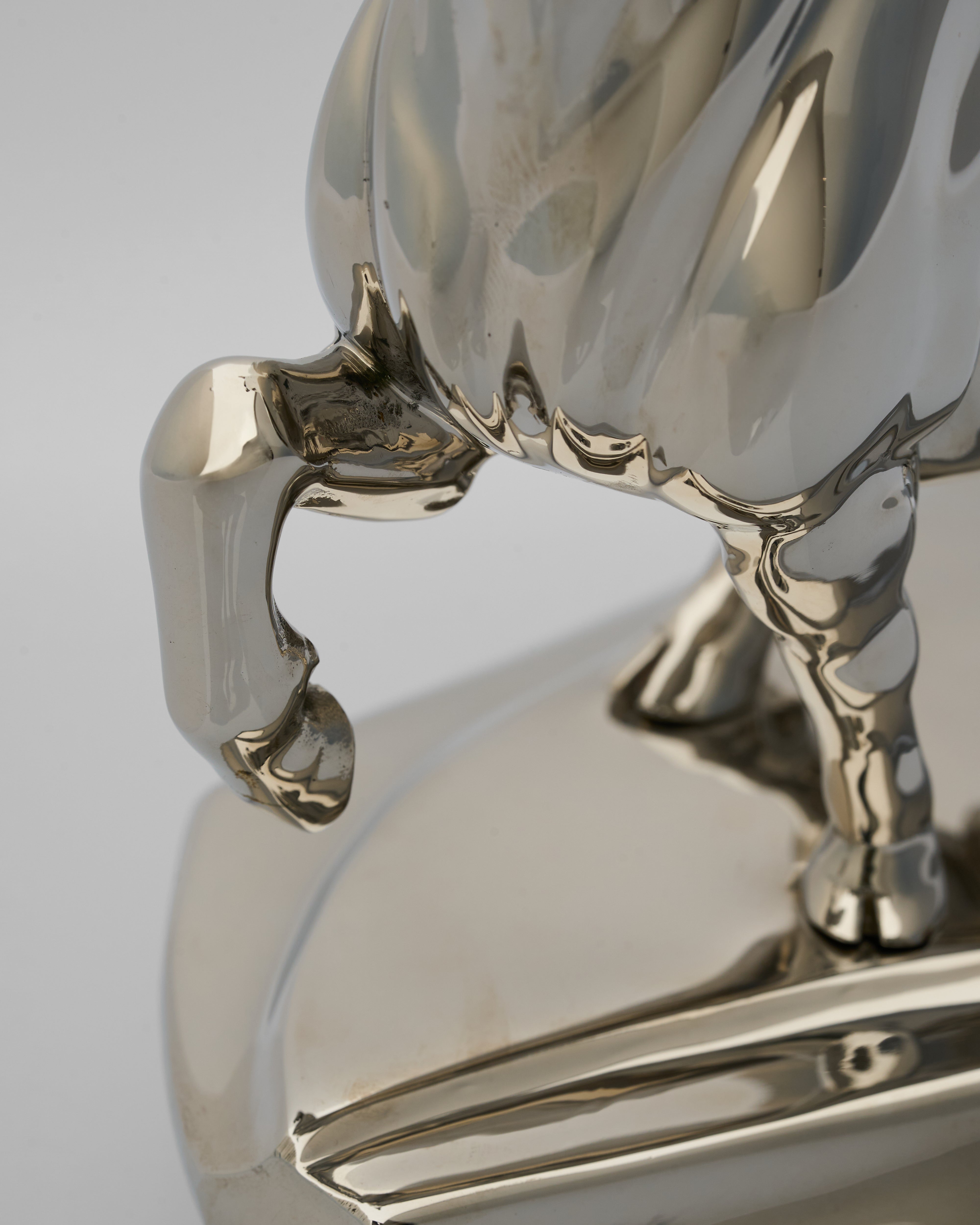 Close-up of a shiny metal bull figurine on a light gray background