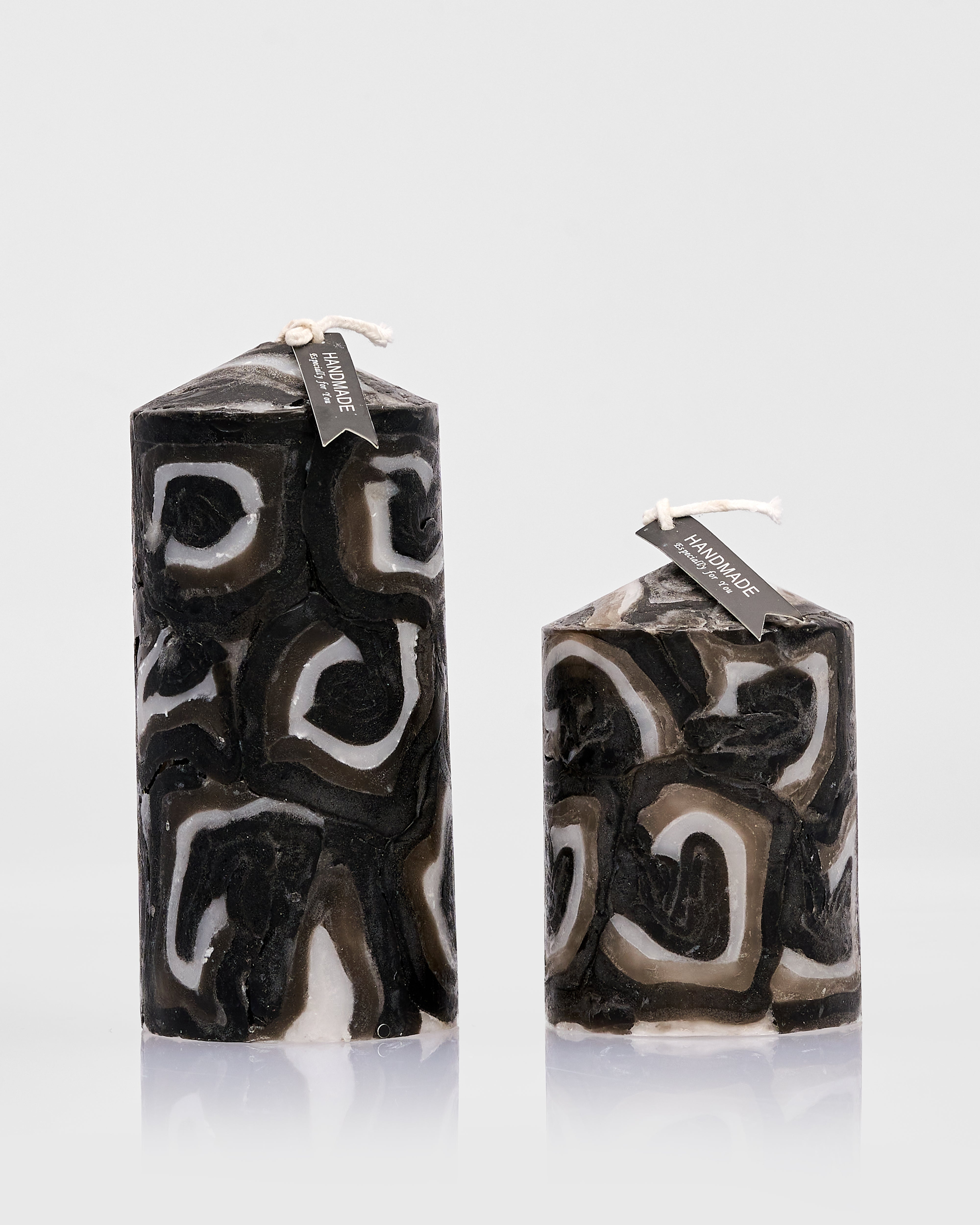 Two marbled black and white candles on a light gray background
