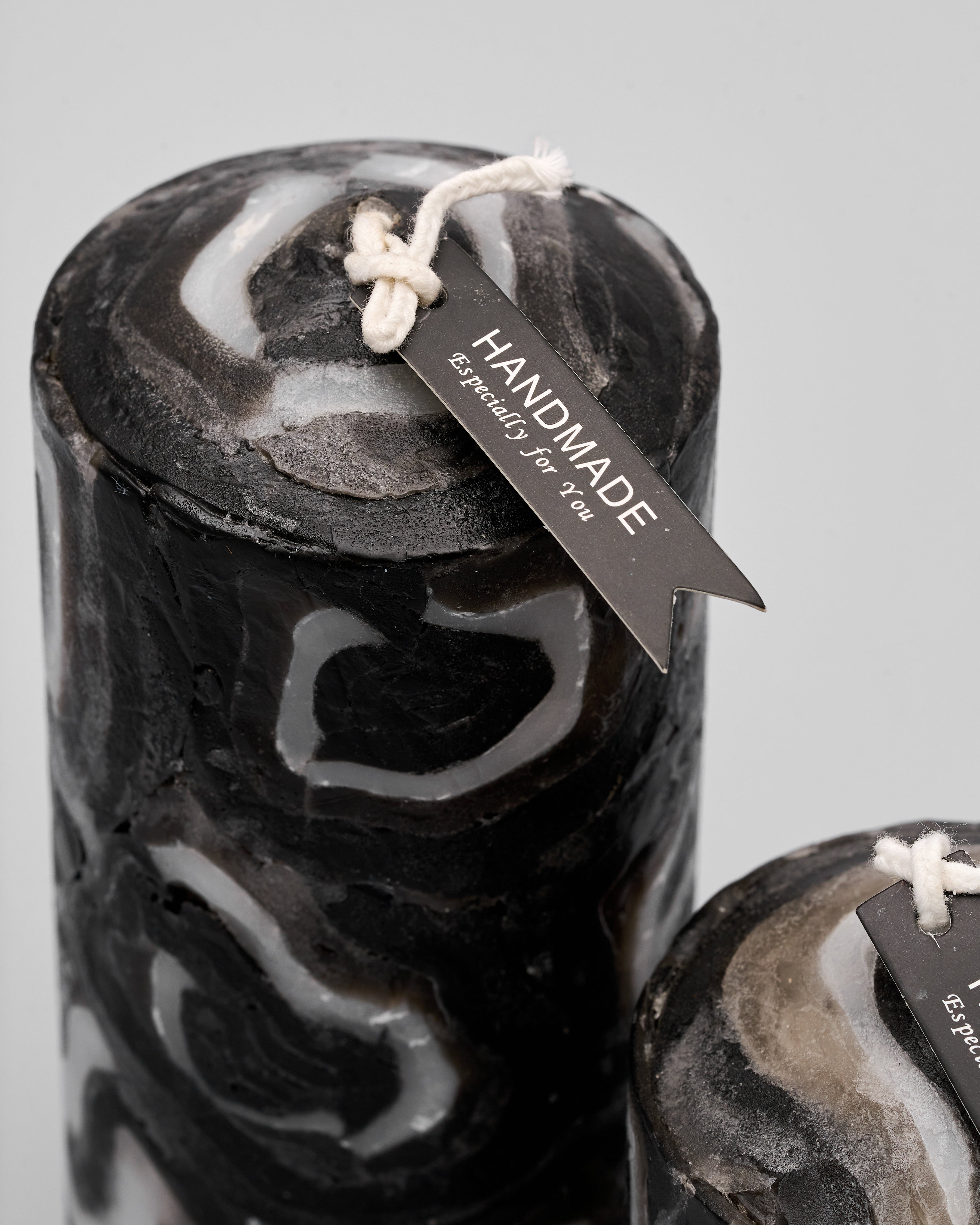 Black and white marbled candles with 'Handmade' tags on a gray background