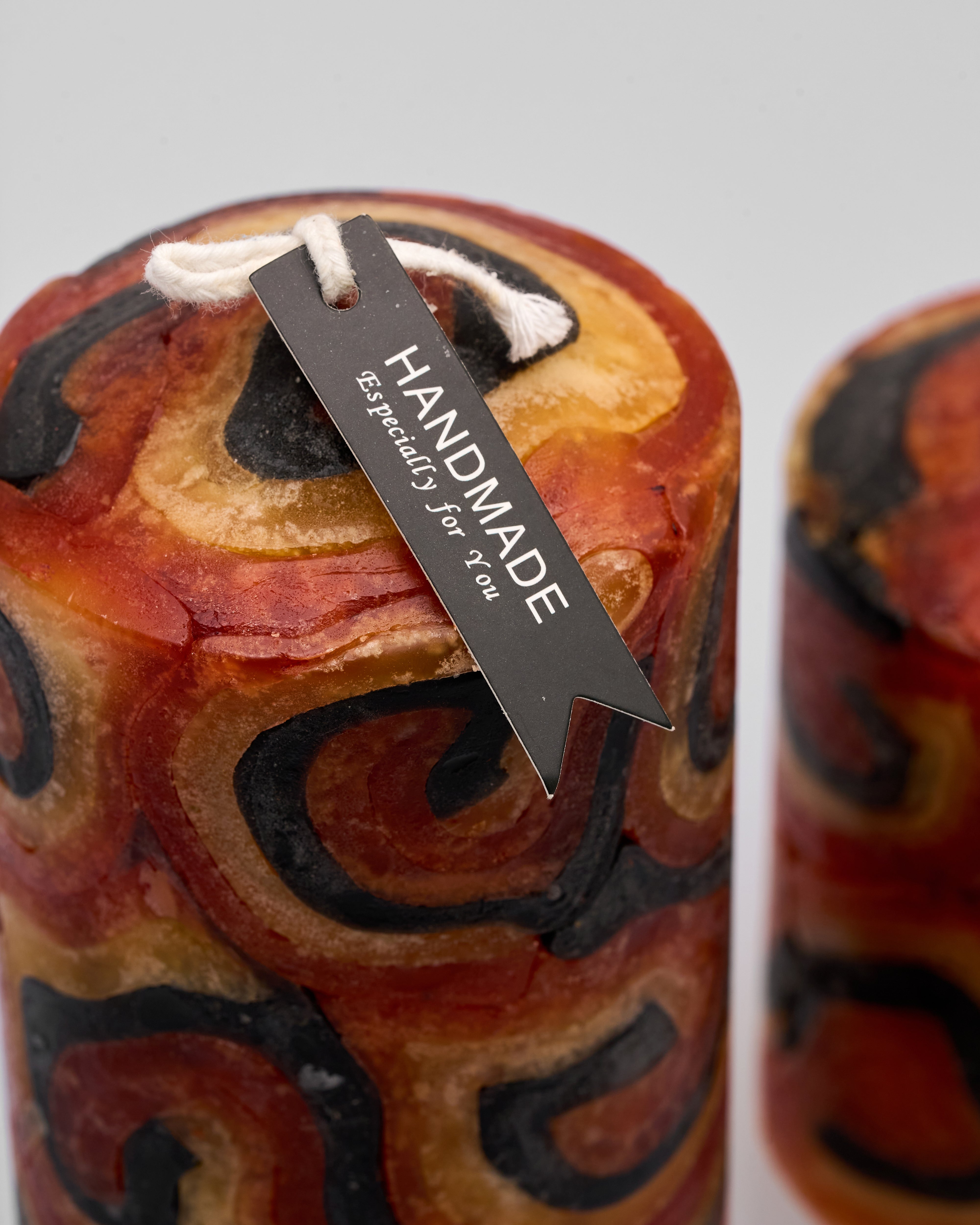 Decorative candle with a 'Handmade' tag on a gray background