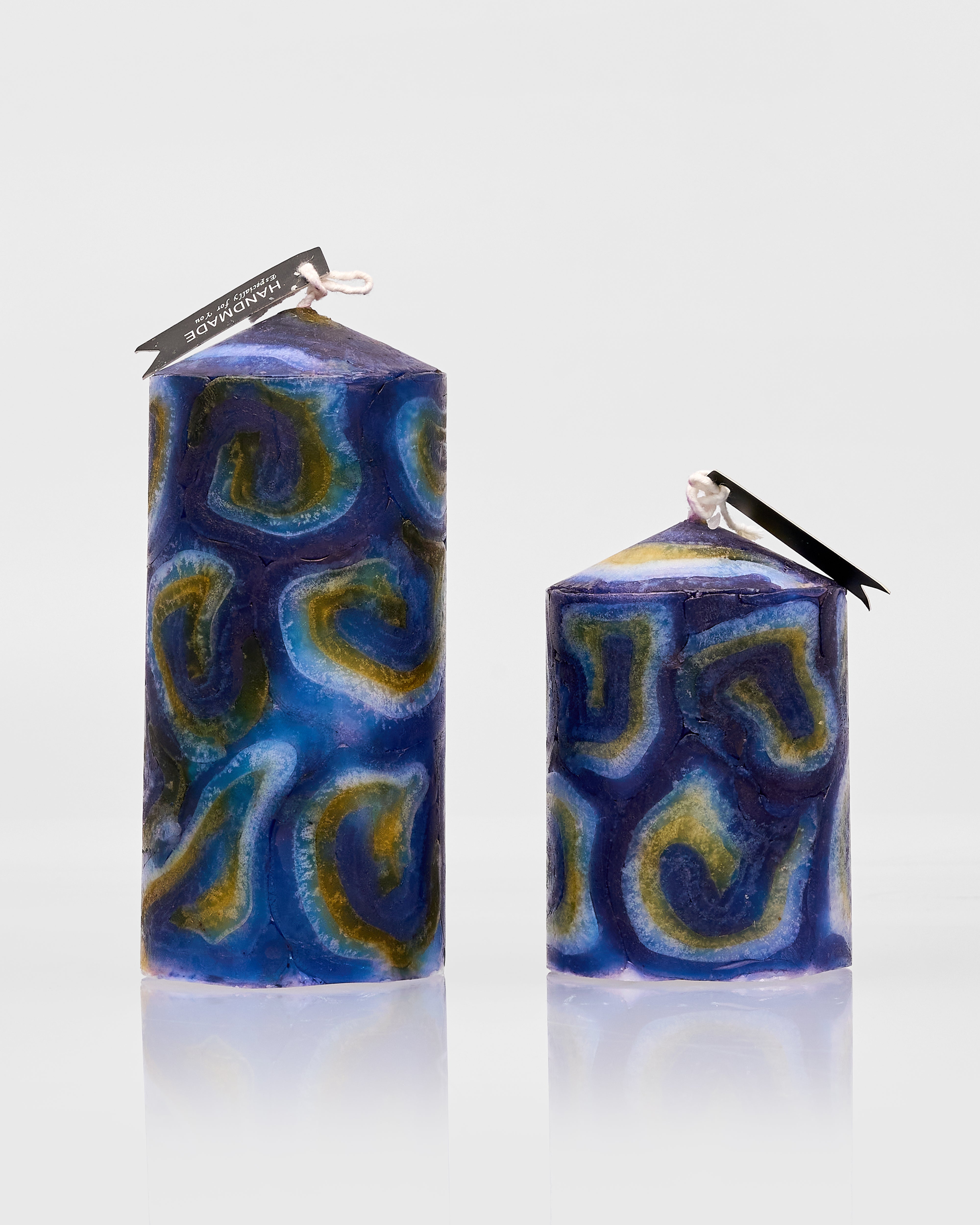 Two blue and green patterned candles on a white background