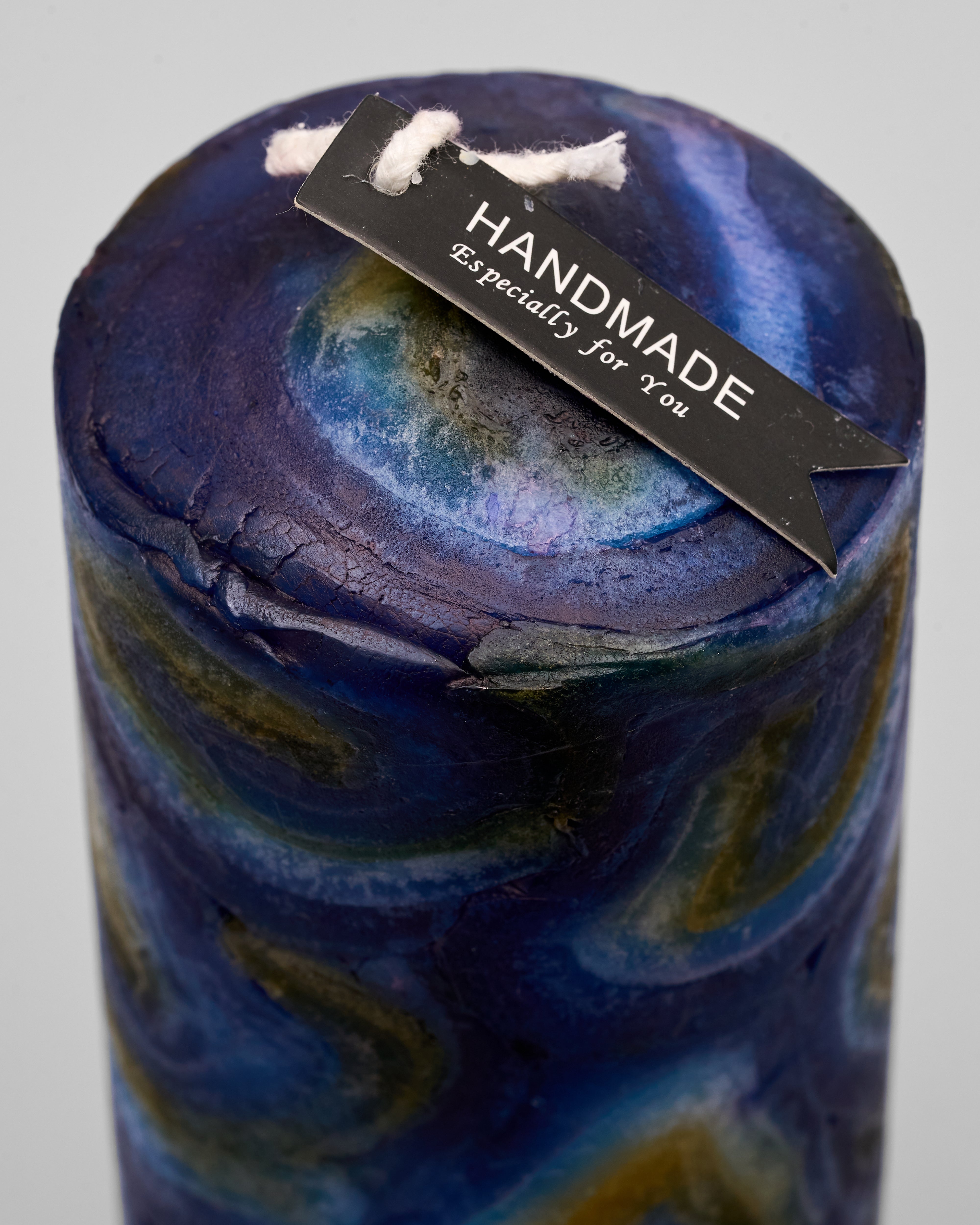 Blue marbled candle with a 'Handmade' tag on a gray background