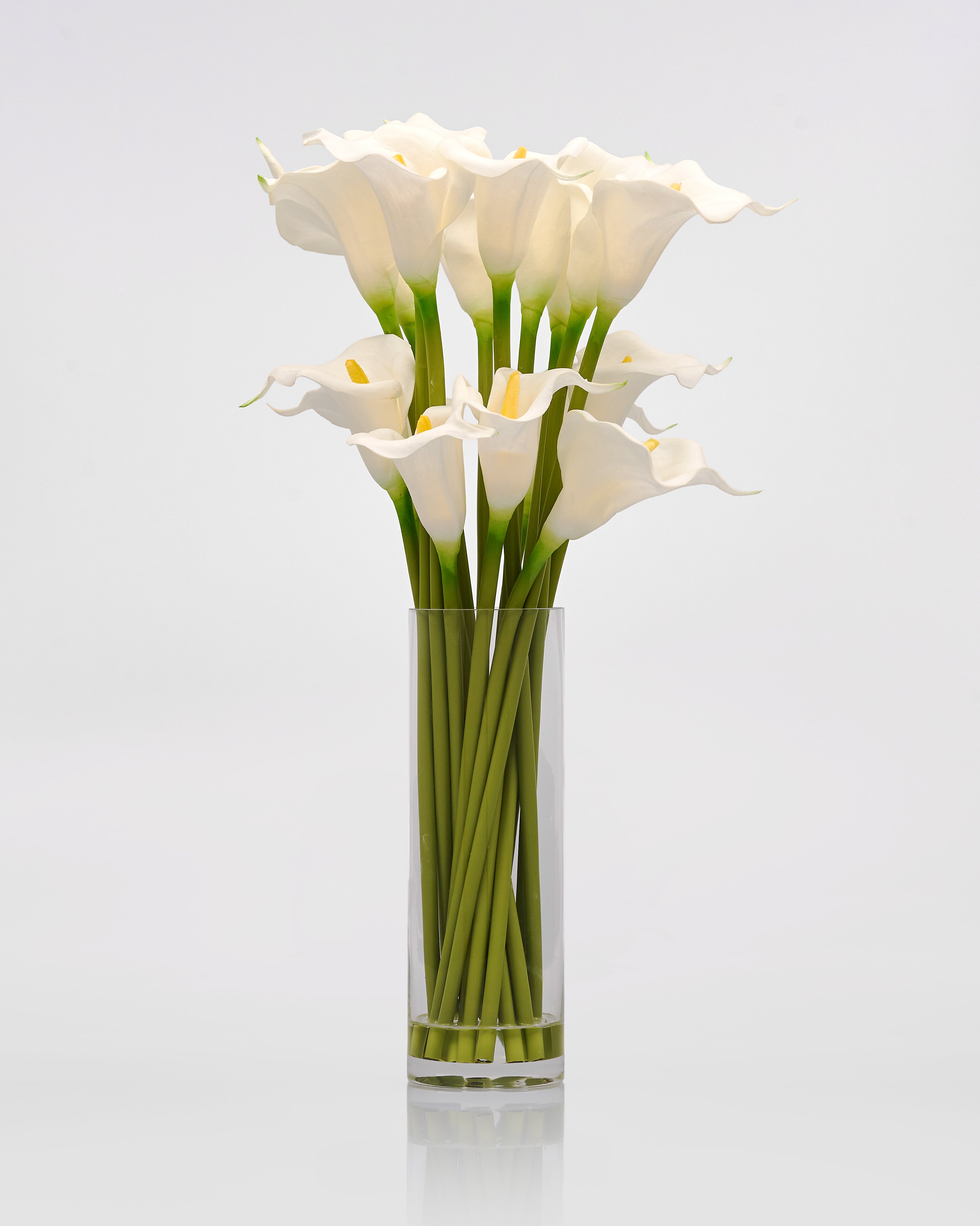 Clear glass vase with white calla lilies Artificial Flowering Plant on a light gray background