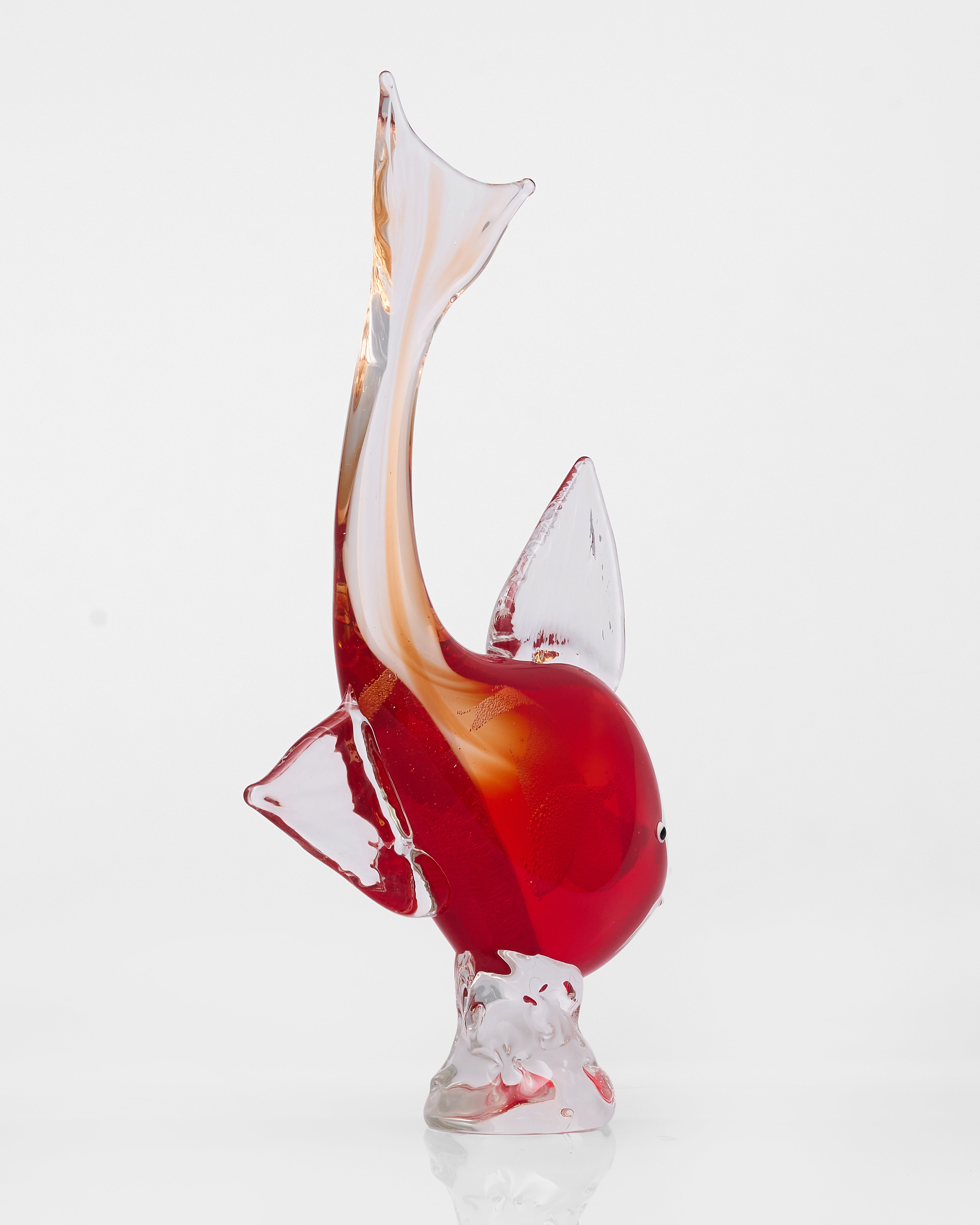 Glass sculpture of a fish with red and orange swirls on a white background