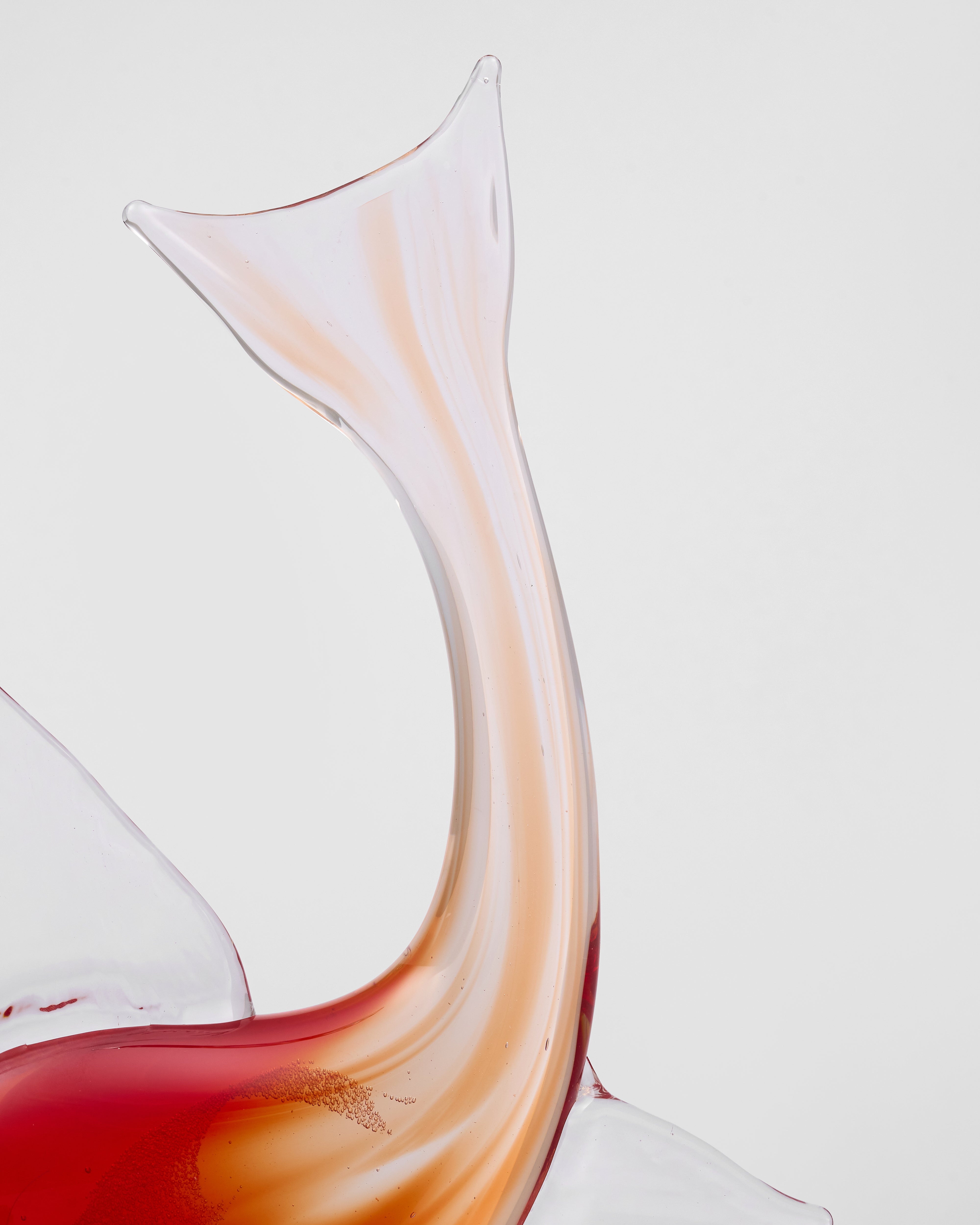 Close-up of a Kairo Red Crsytal Glass Fish Decor with red wine on a light gray background