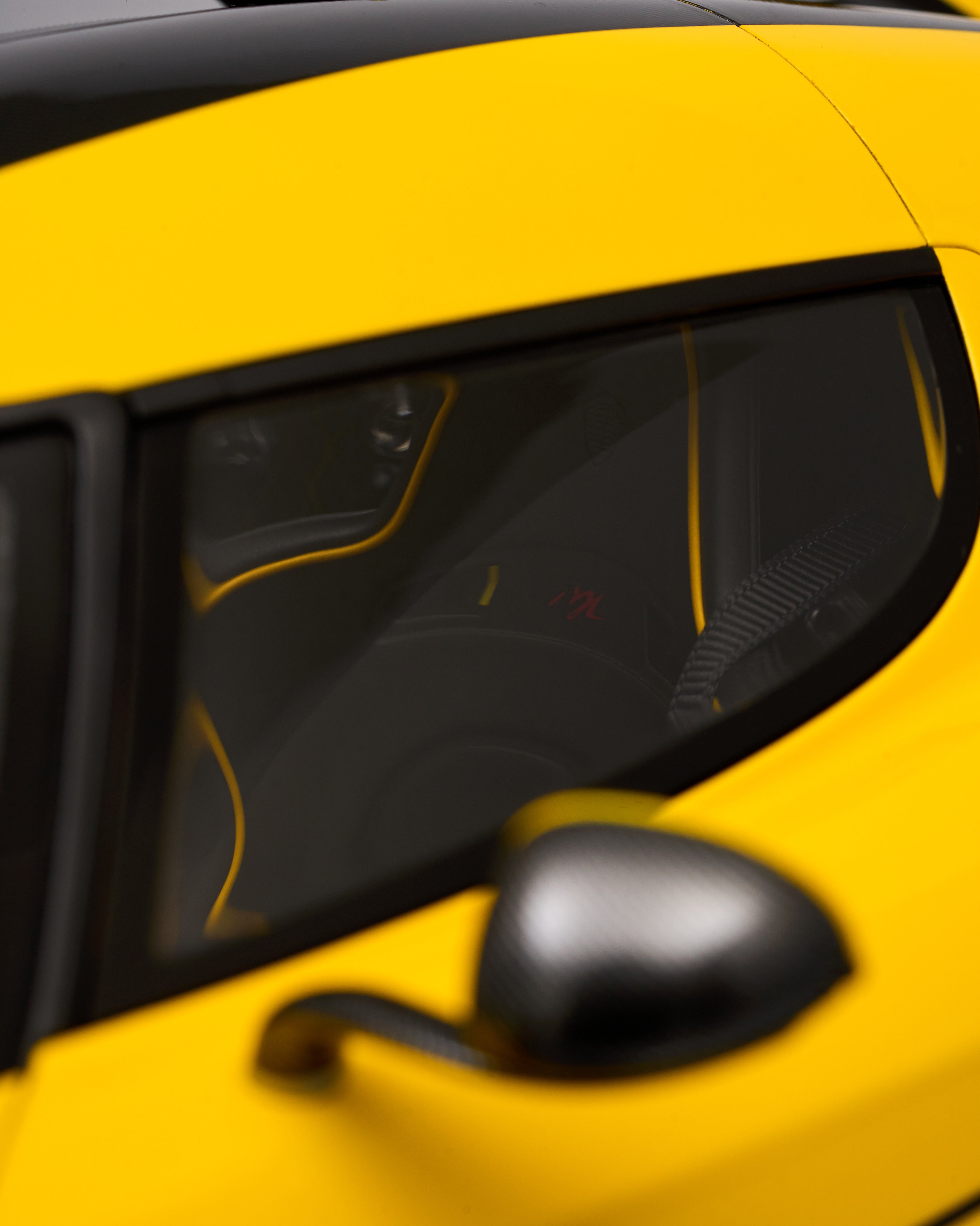 Close-up of a yellow car's side mirror and window and seats