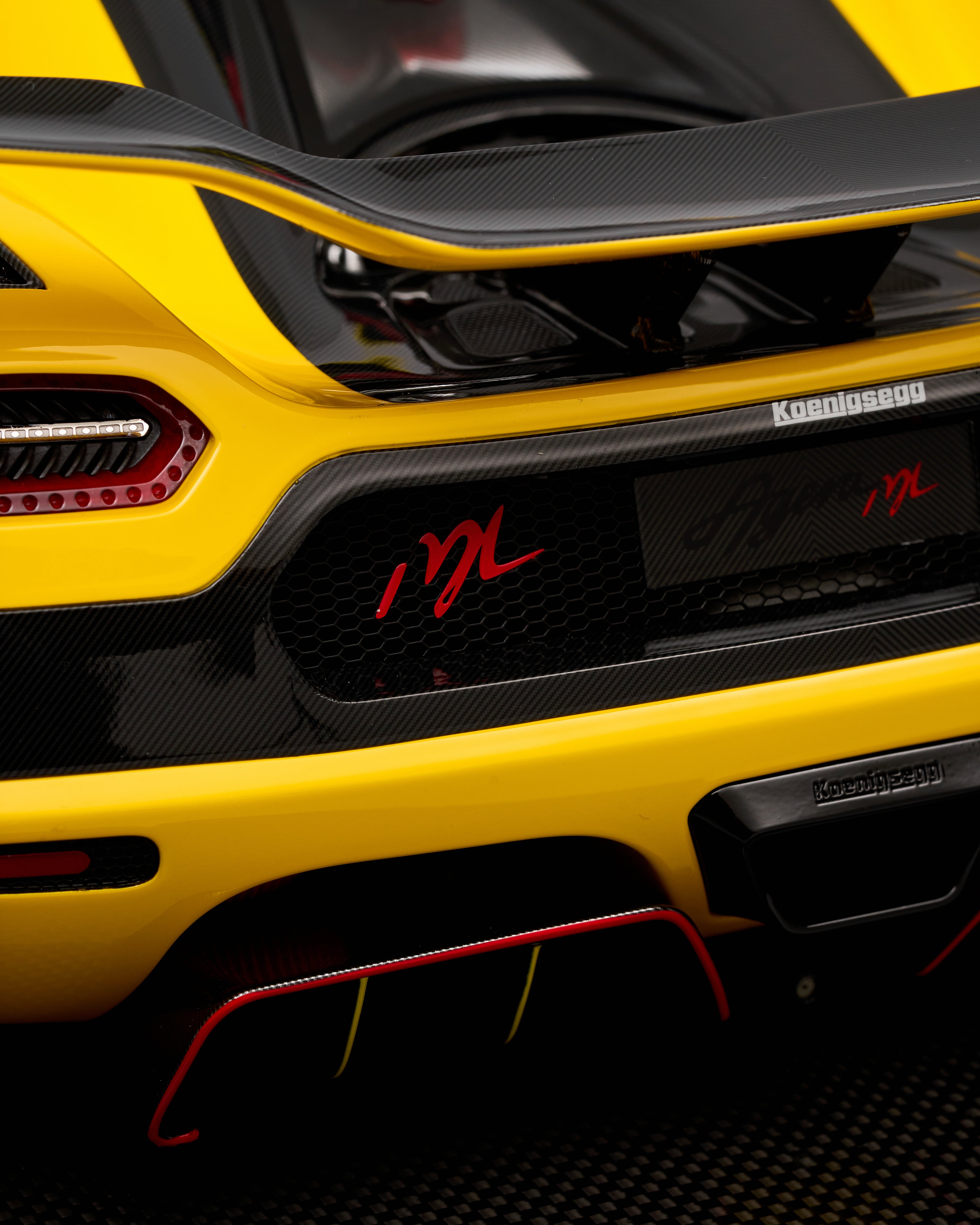 Close-up of a yellow sports car with carbon fiber elements and branding.