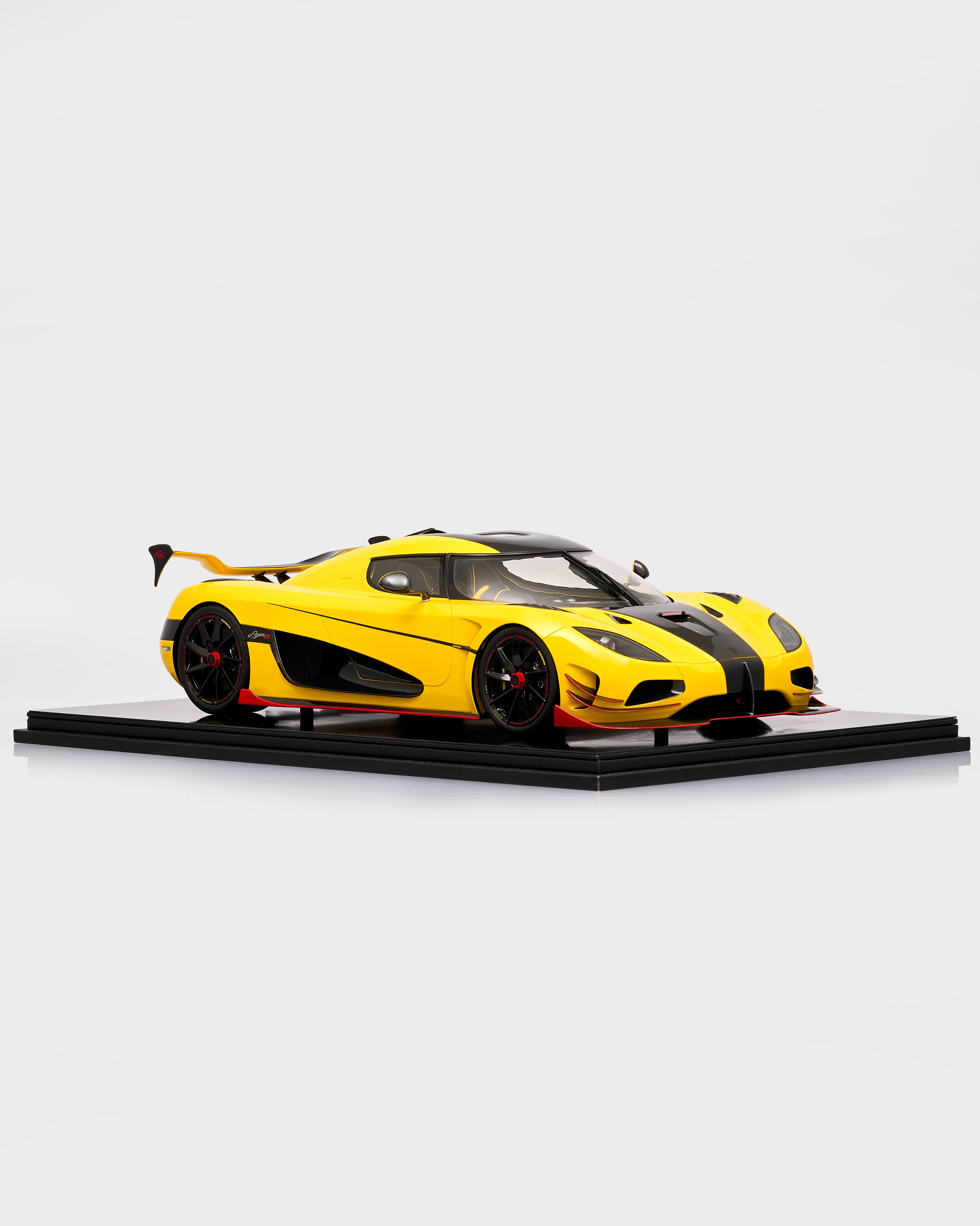 Yellow sports Koenigsegg Agera 1:8 Carbon Model car model on a black platform with a white background