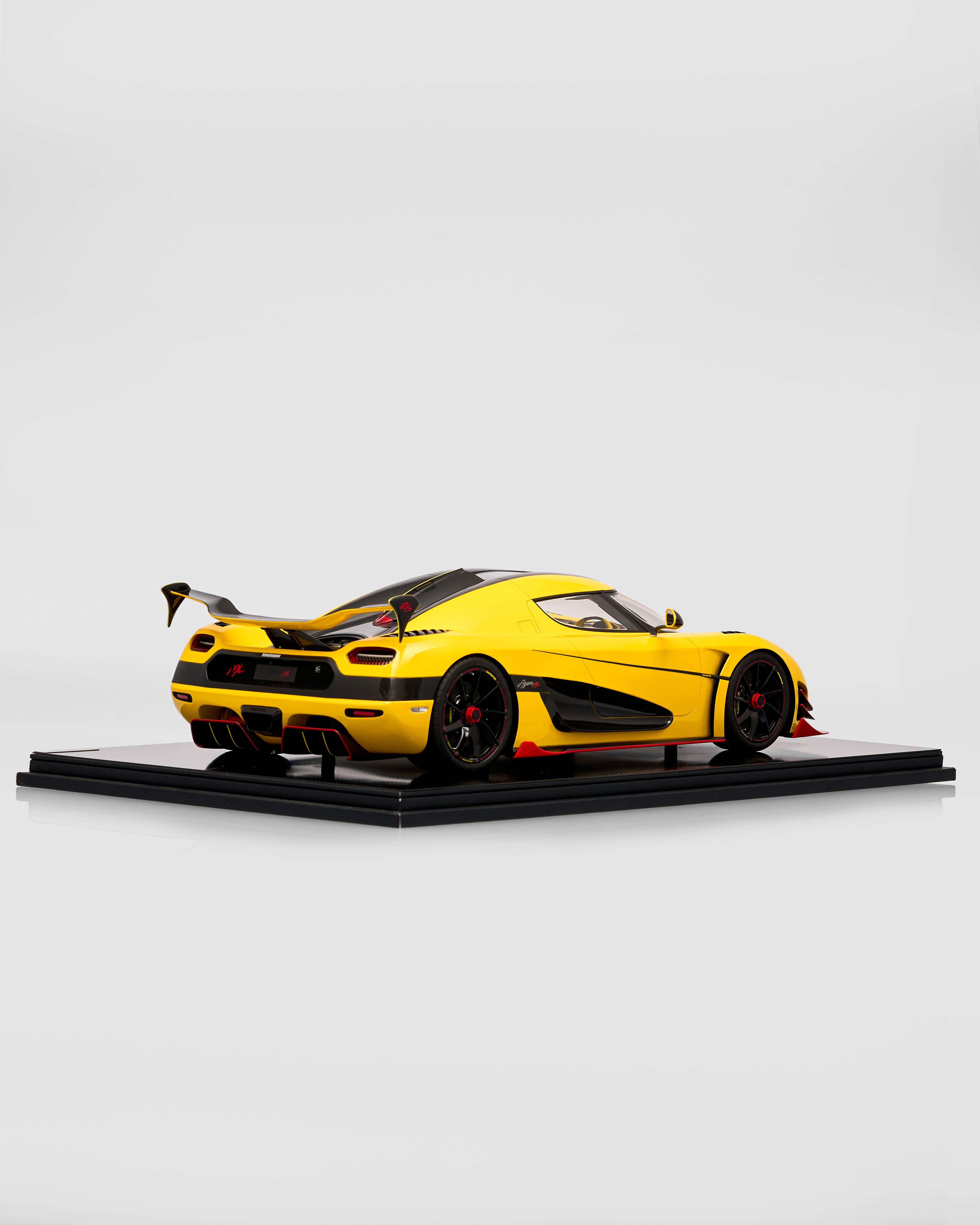 Yellow sports car model on a black platform with a white background