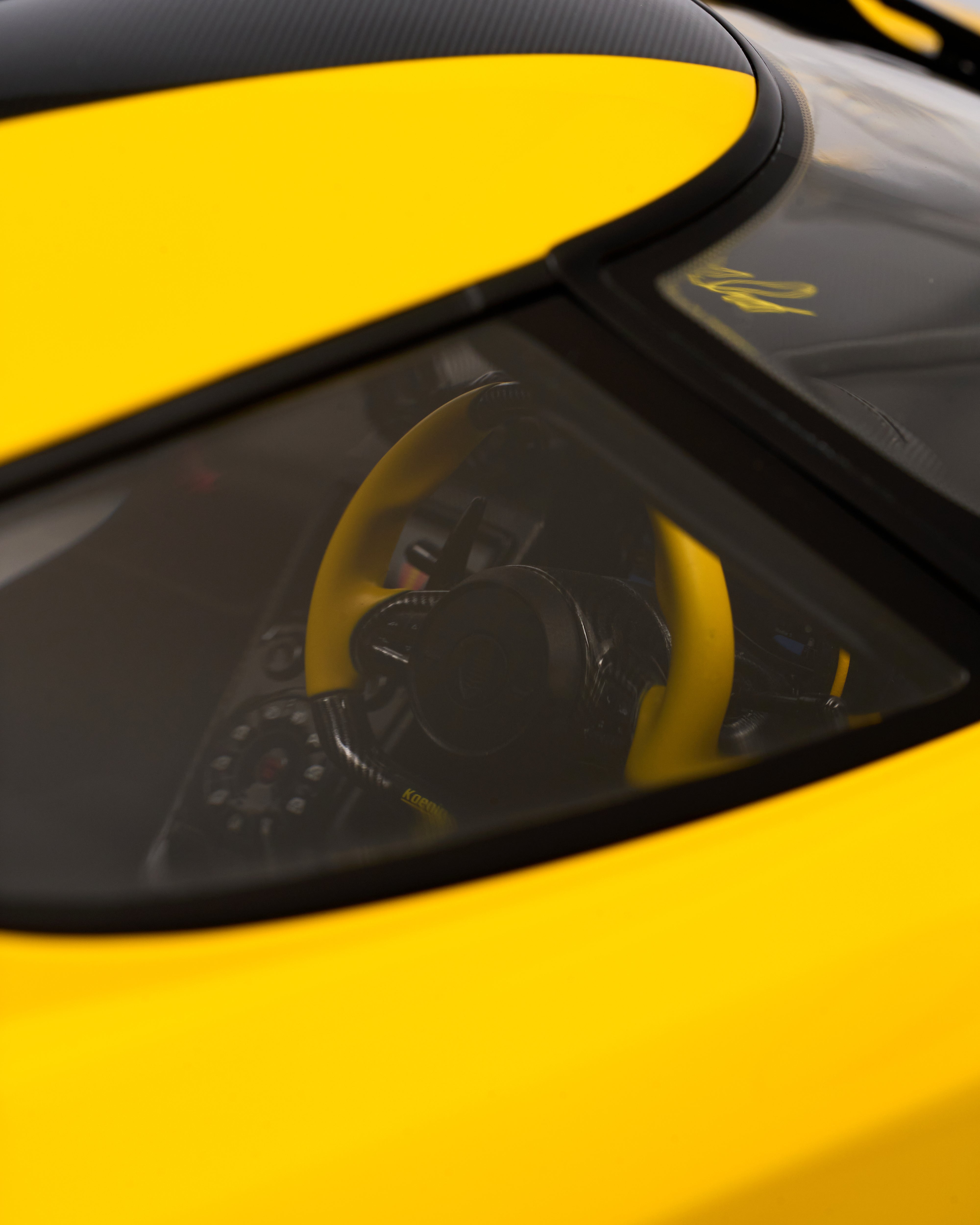 Close-up of a yellow car's steering wheel with a visible brand logo.