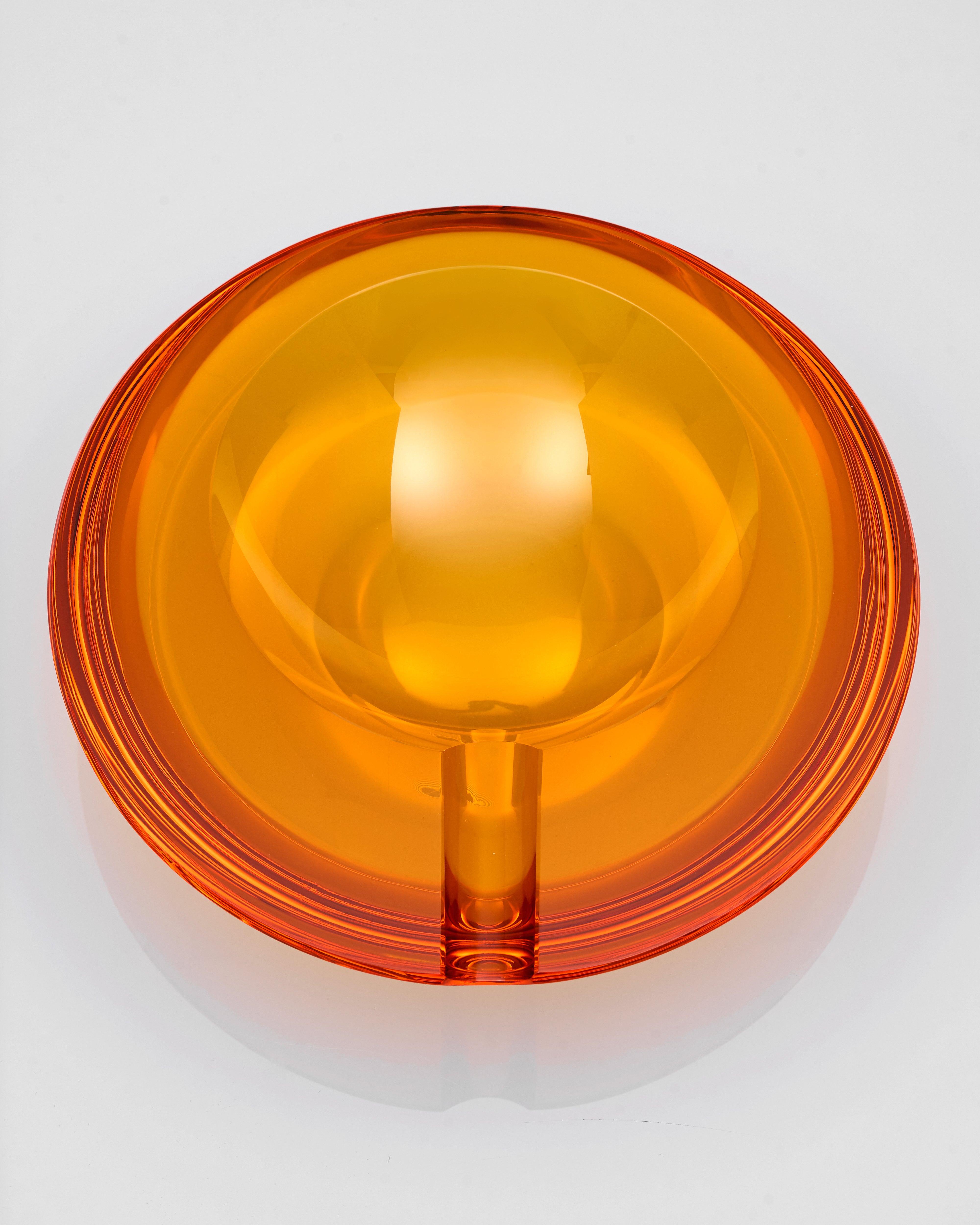Orange circular crystal glass ash tray on a white background
