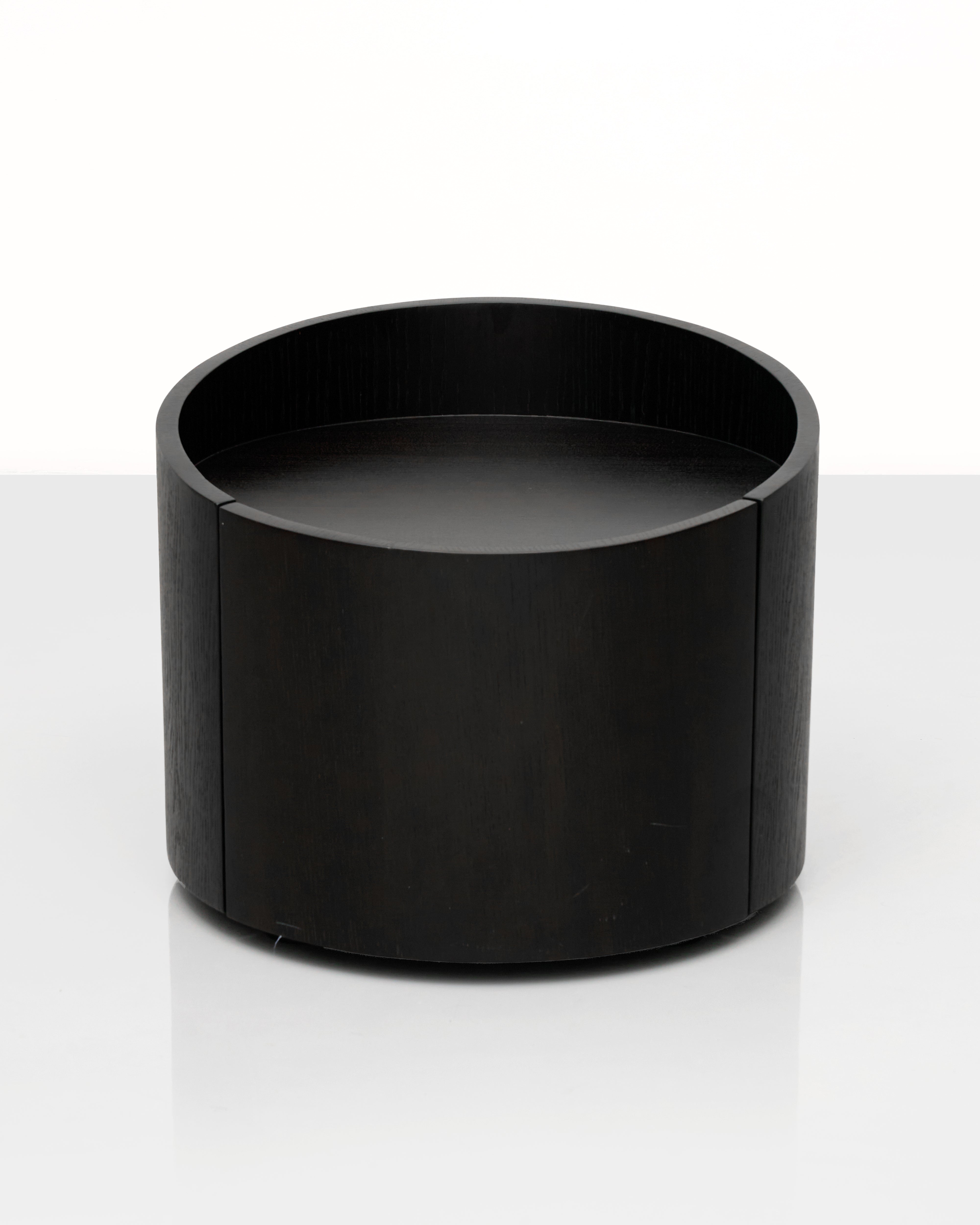 Black cylindrical side table with drawer on a white background