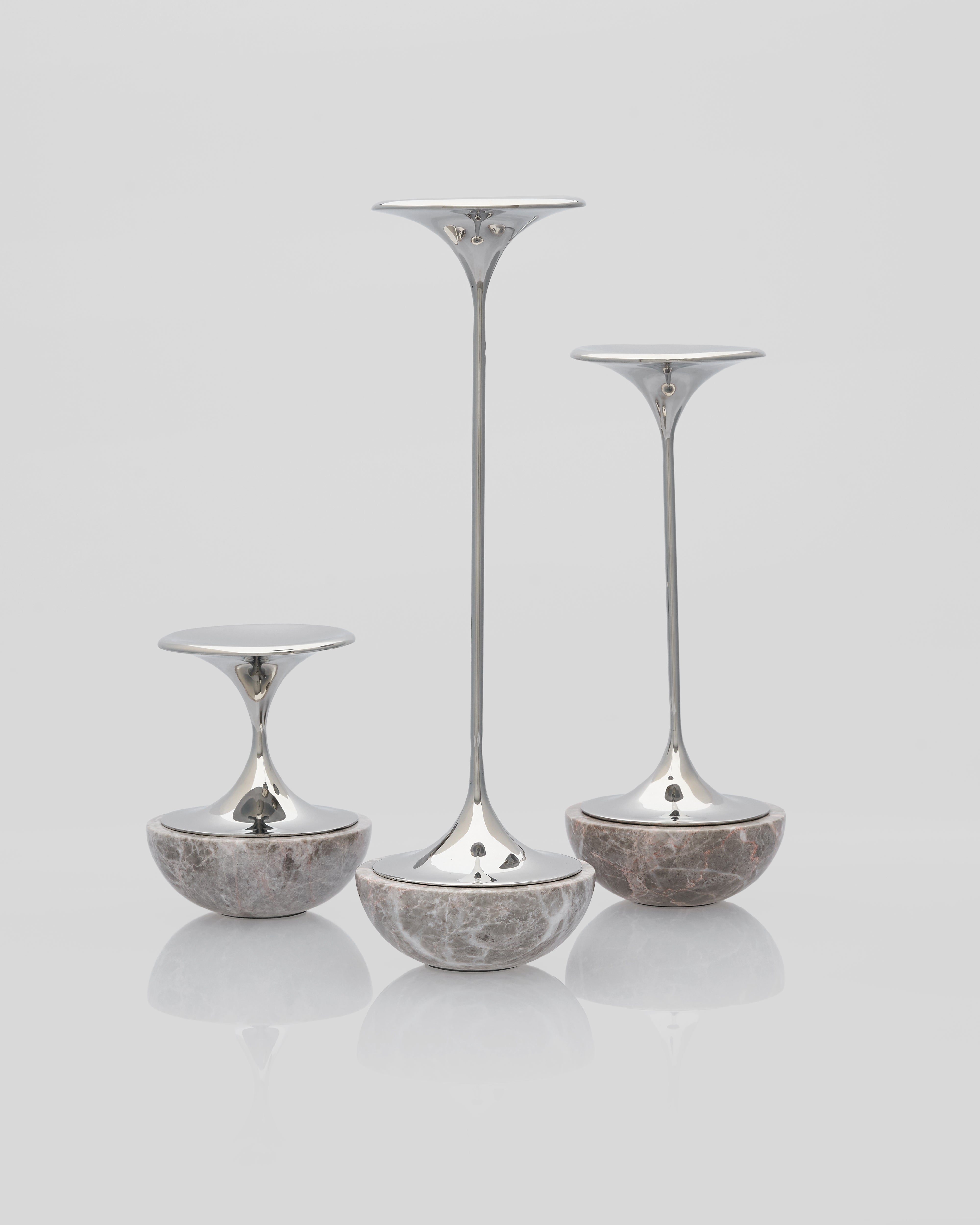 Set of three silver and marble candle holders on a light gray background