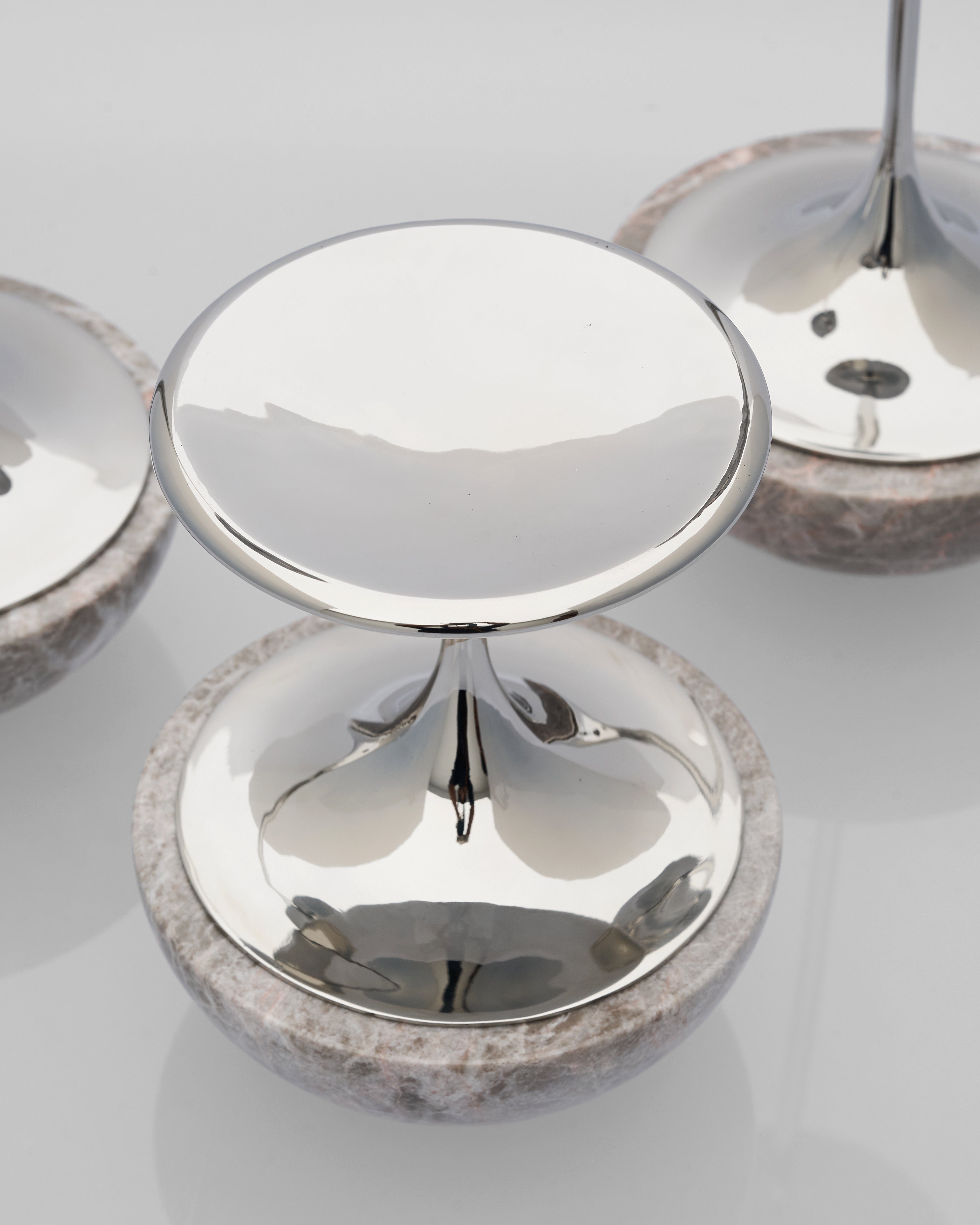Close-up of metalliccandle holder with marble base objects on a reflective surface