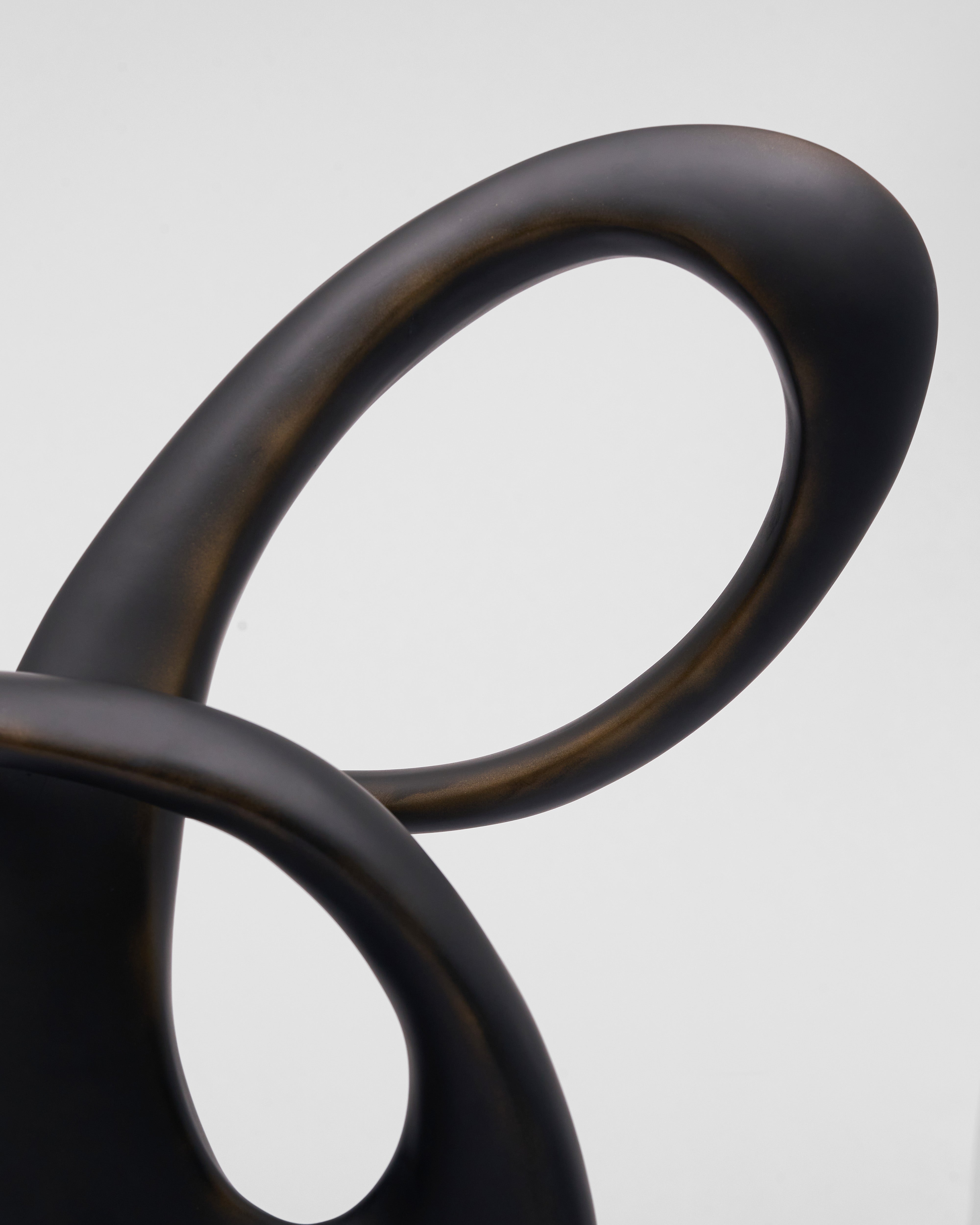 Close-up of a black Lunea Infinity Sculpture with a curved design on a light gray background