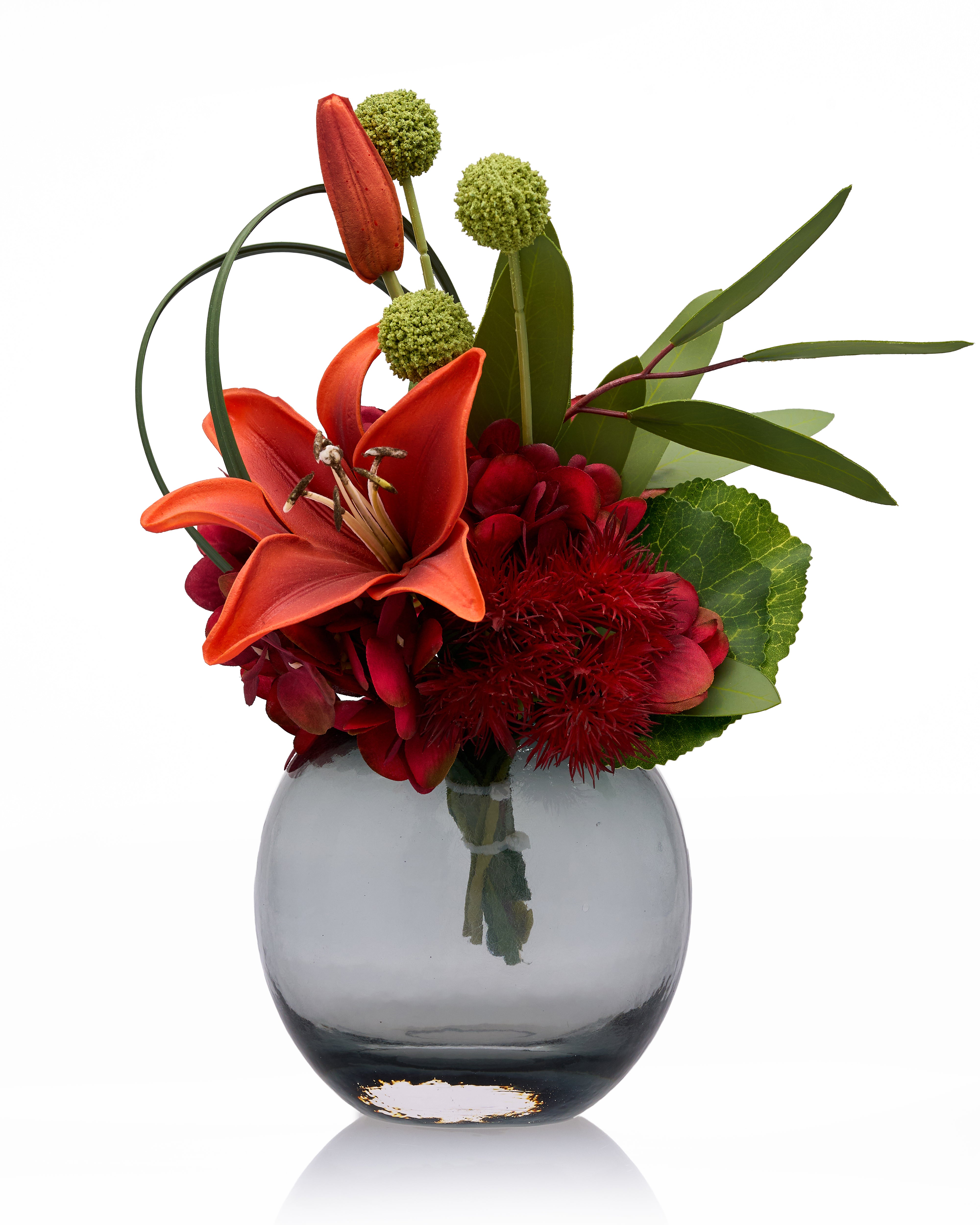 Floral arrangement with red and green flowers in a clear vase on a white background