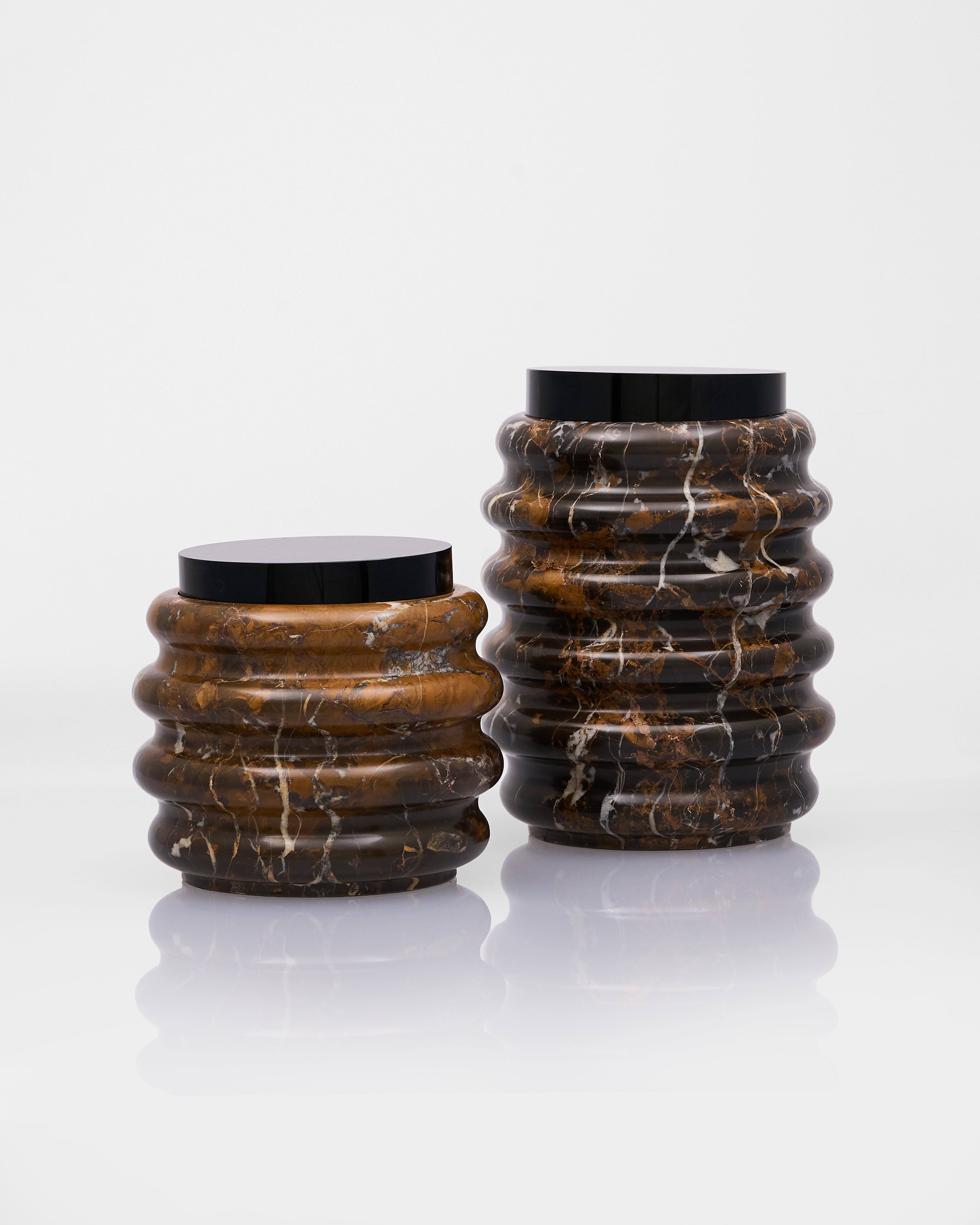 Two marble-textured cylindrical vases with black lids on a white background