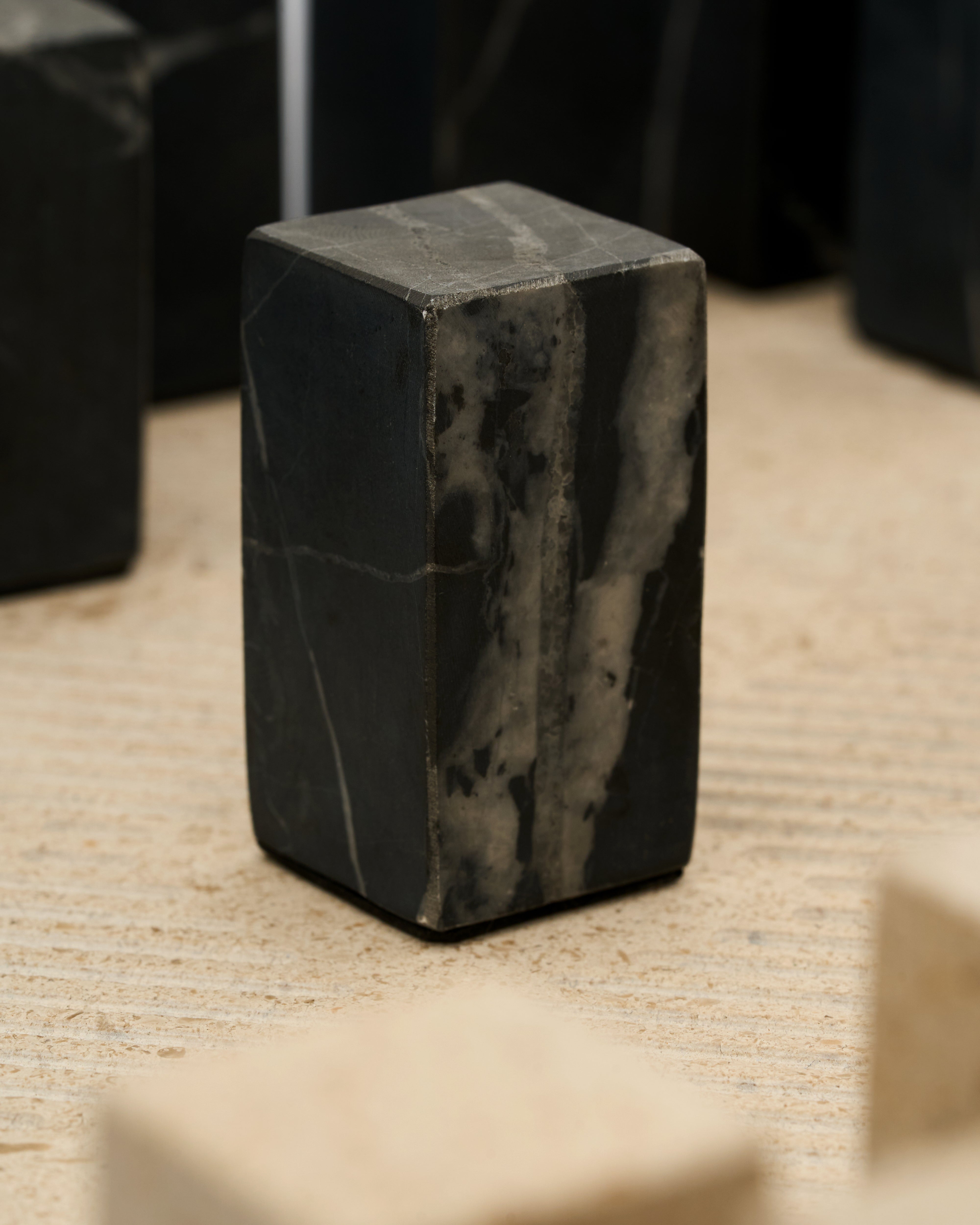 Black marble cube on a textured beige surface