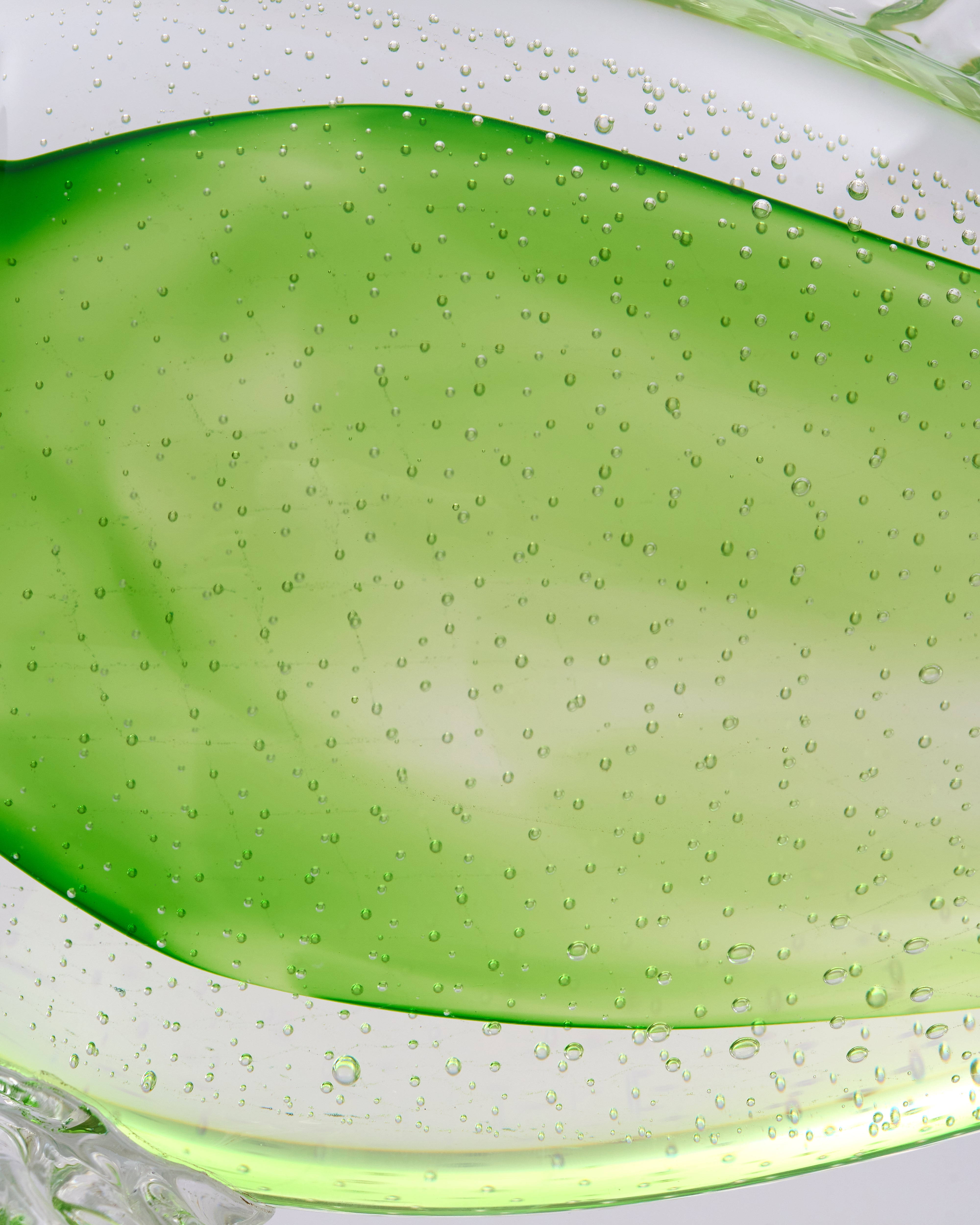 Close-up of green crystal glass with bubbles on a white background