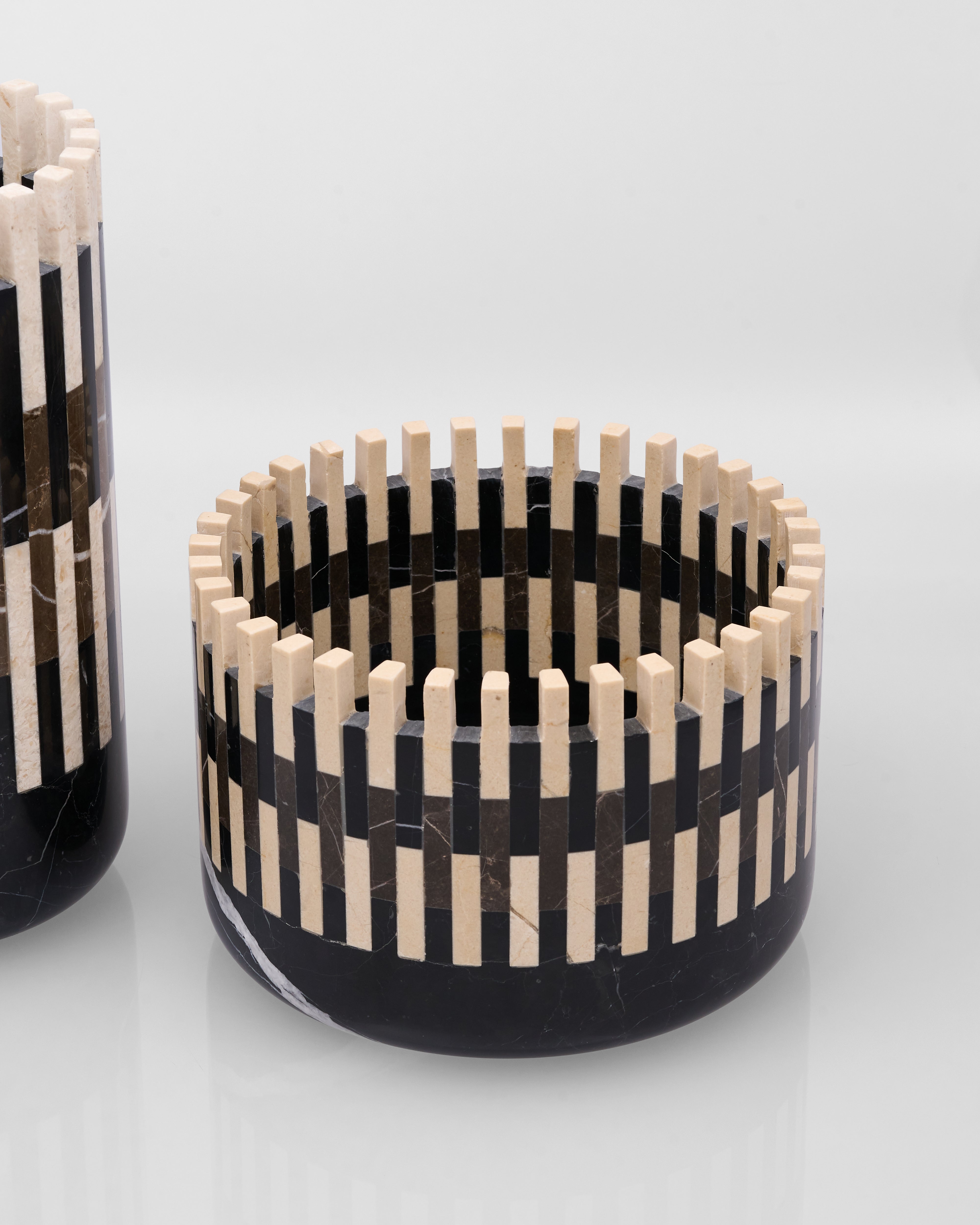 Decorative bowl with black and white striped pattern and wooden accents on a light gray background