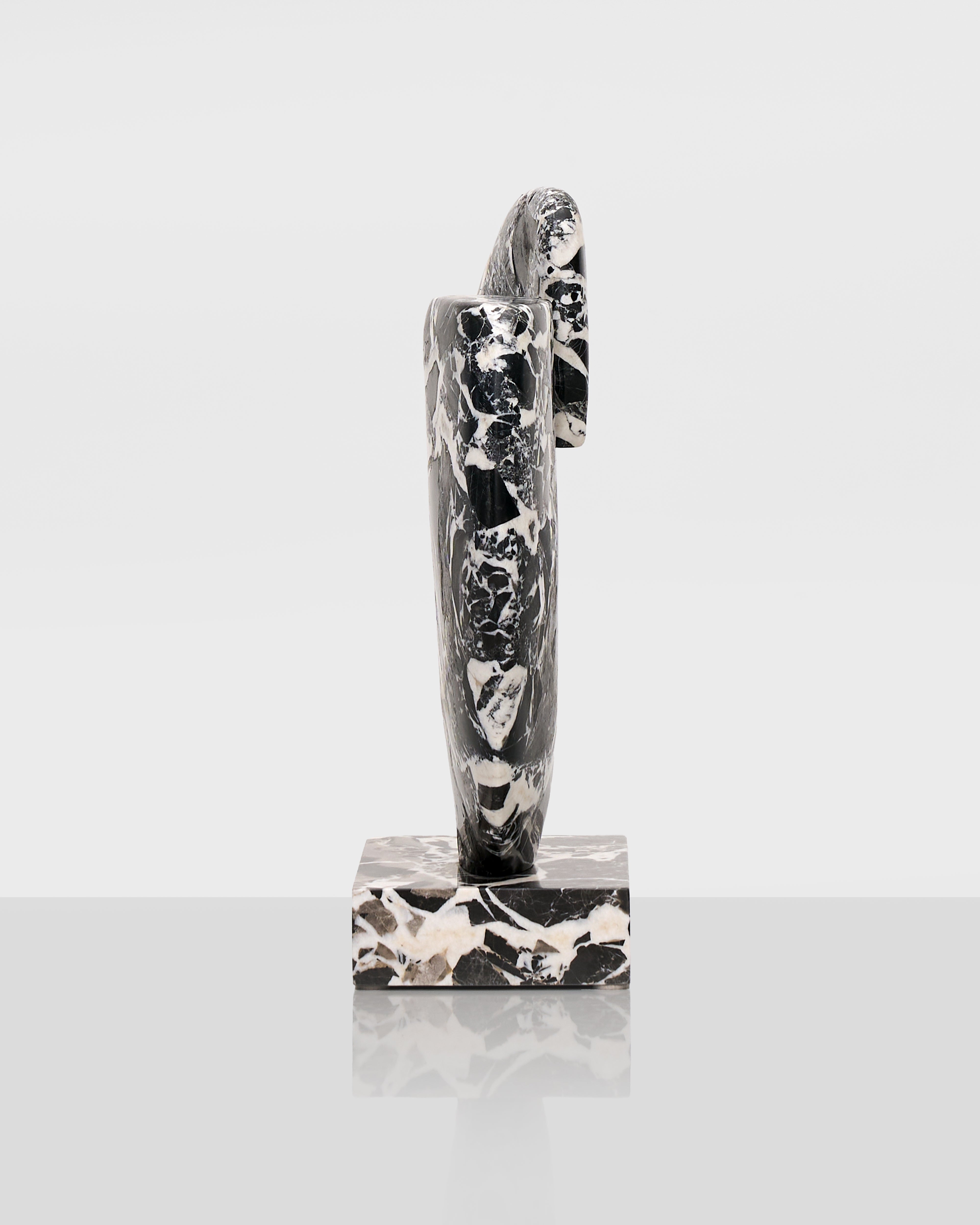 Black and white abstract sculpture on a gray surface with a white background