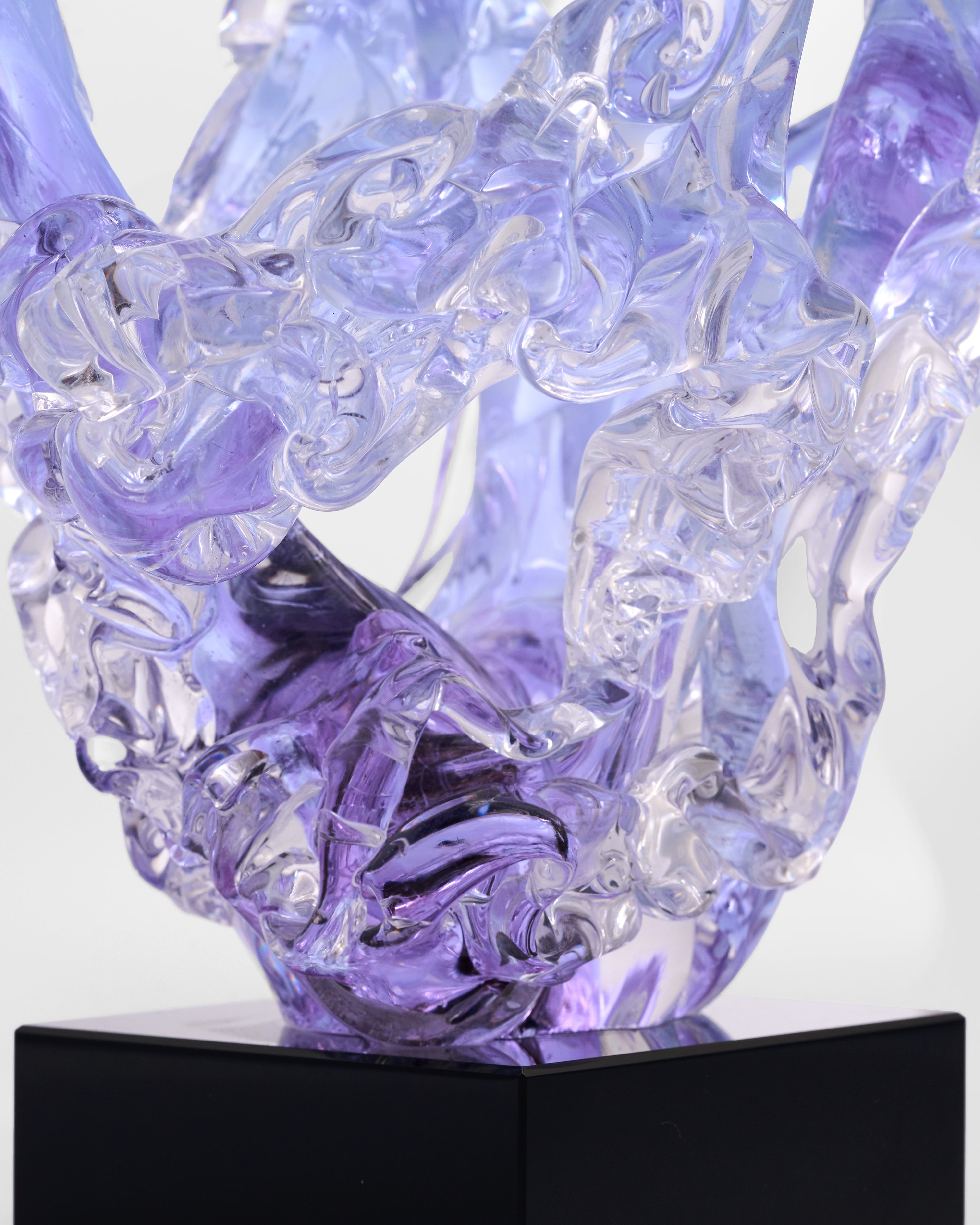 Purple glass sculpture on a black base with a white background