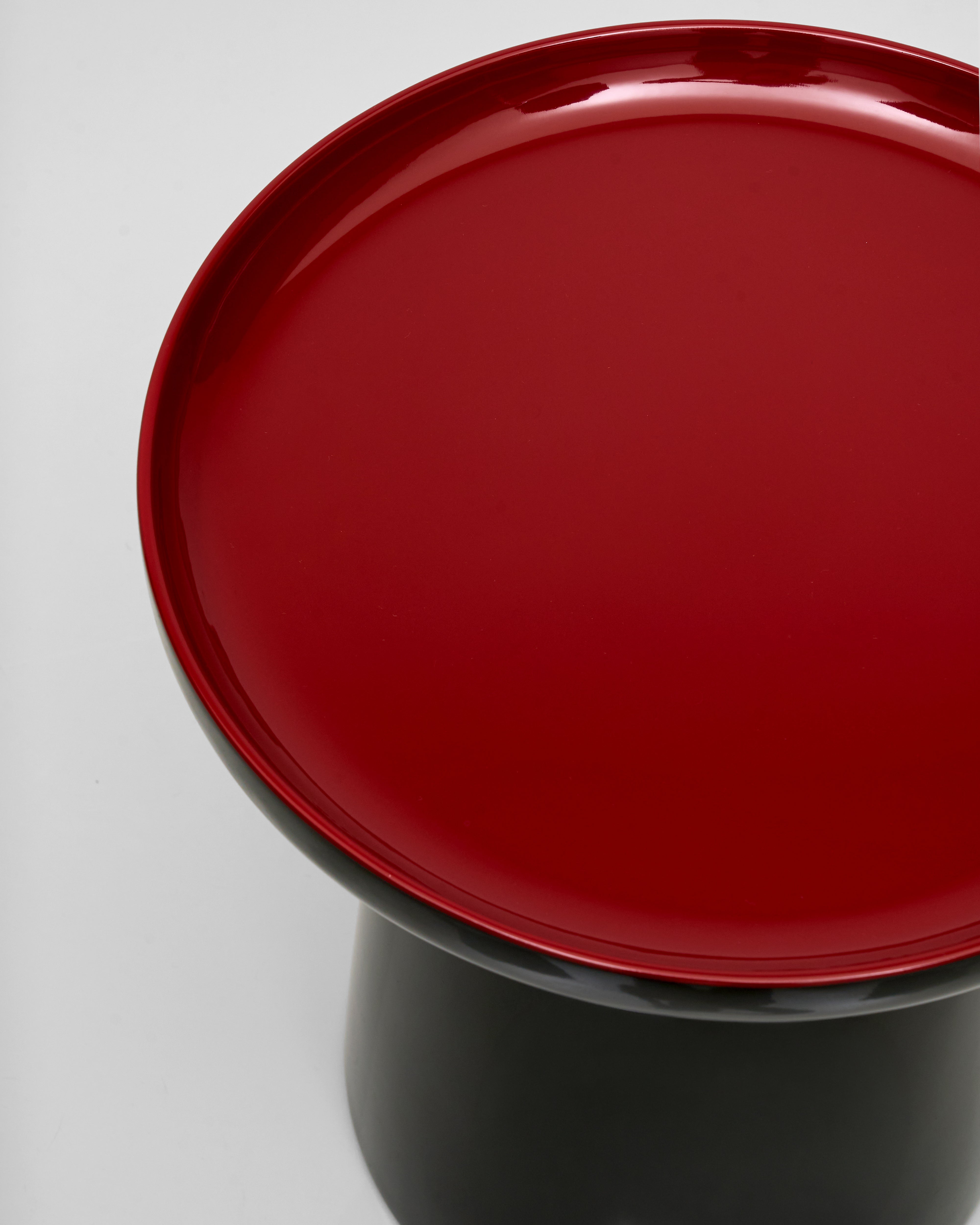 Red top of black side table on a gray background