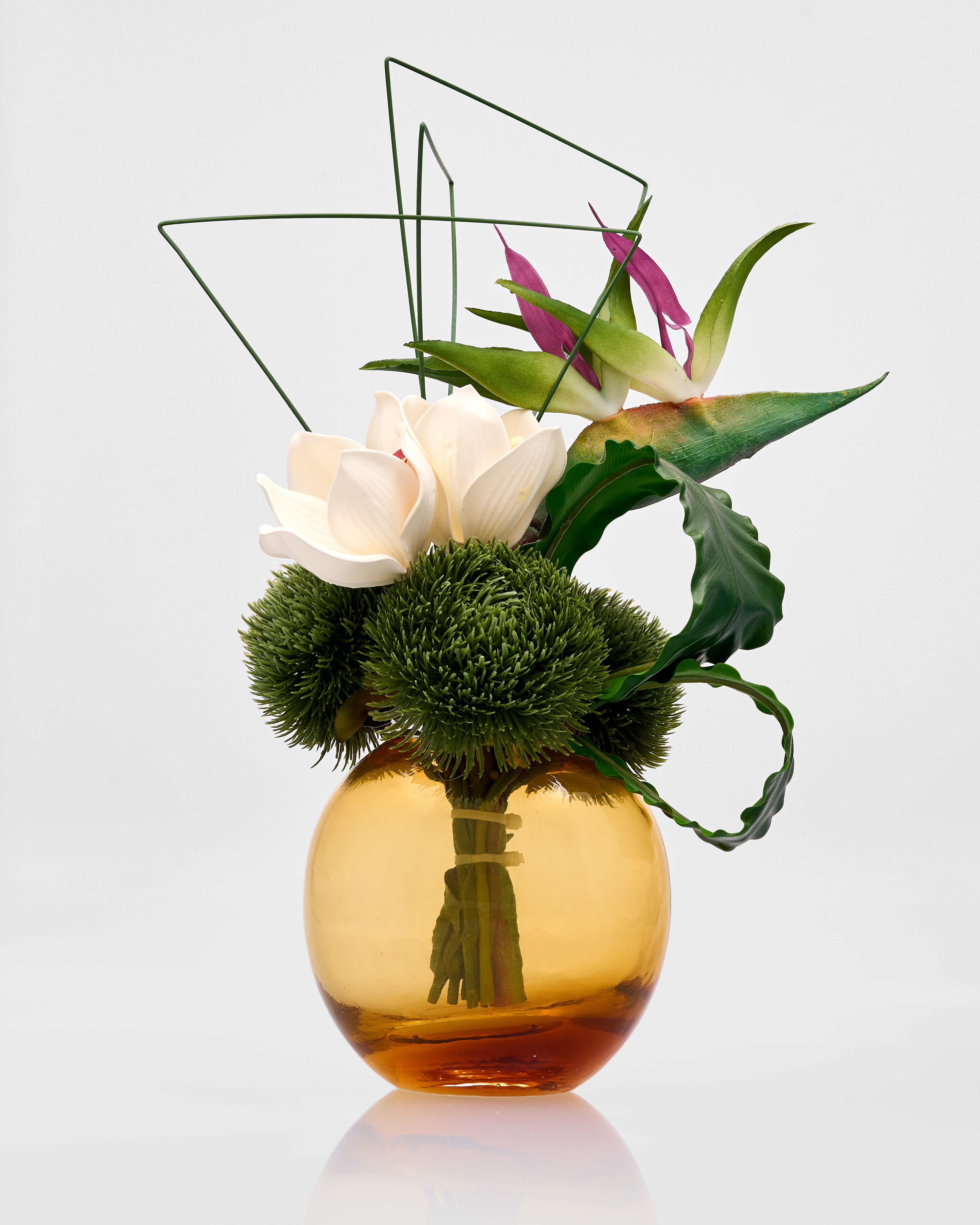 Decorative flower arrangement in a gold vase on a light gray background