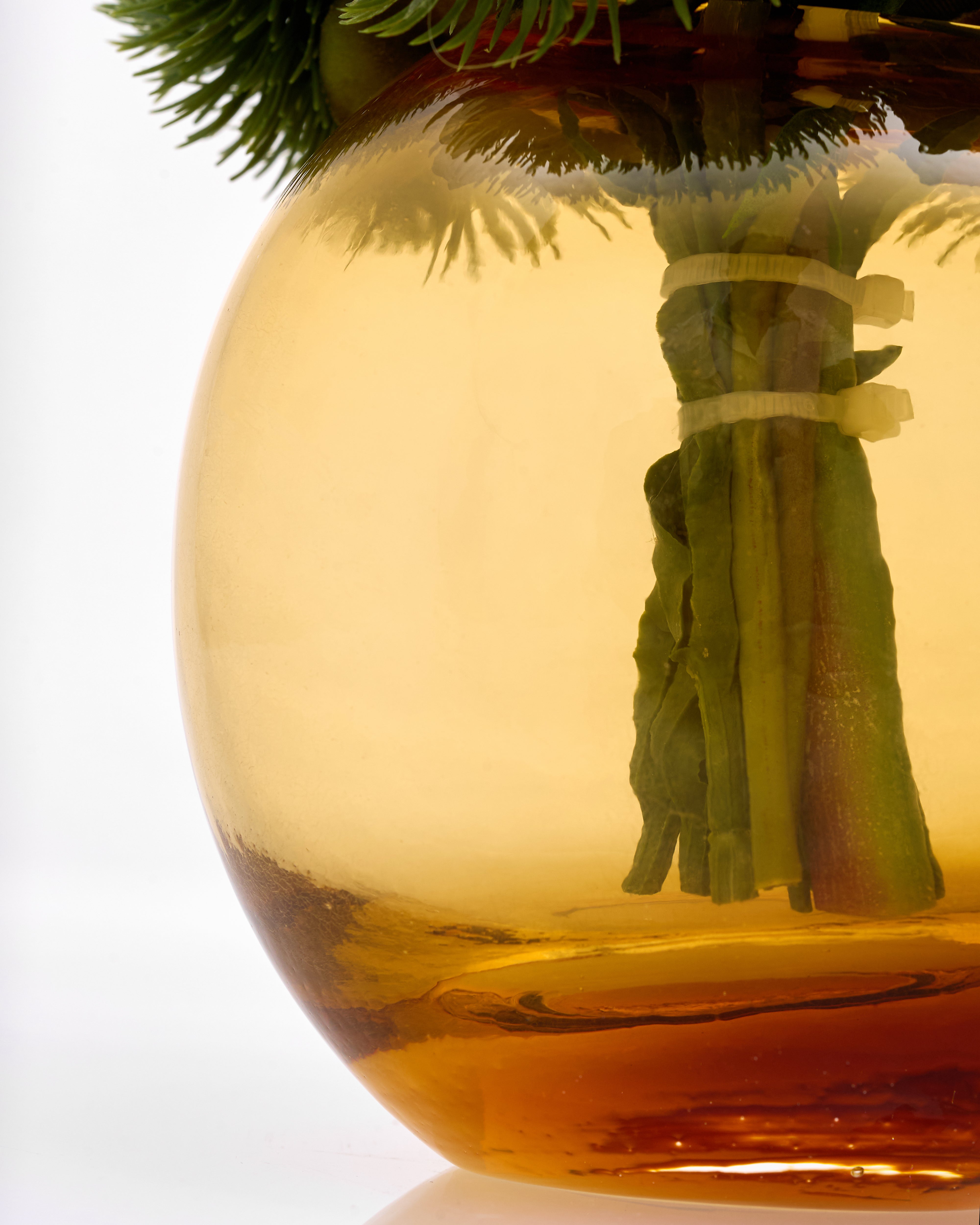 Clear glass ornament with greenery inside on a white background