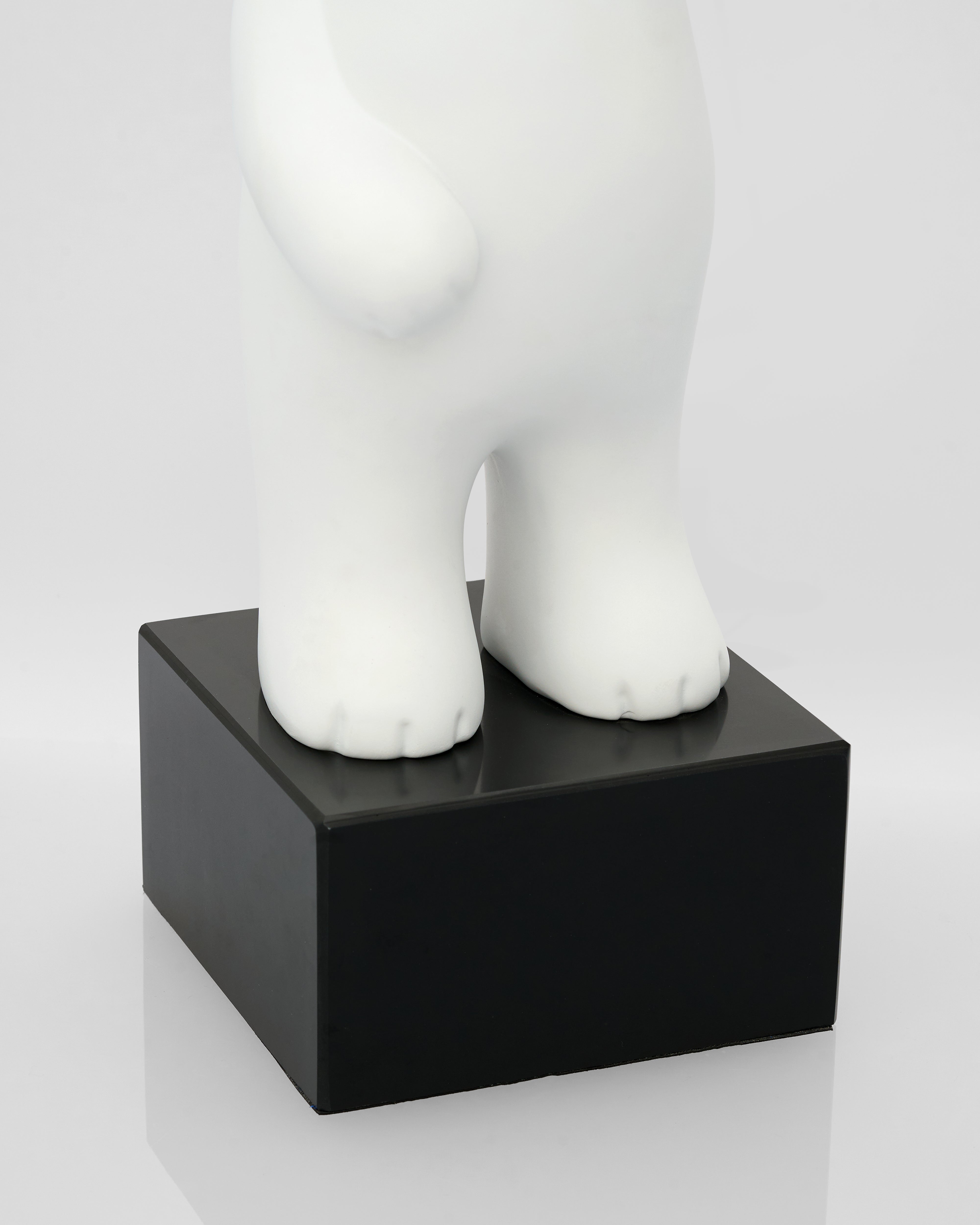 White ceramic bear sculpture on a black square base against a white background