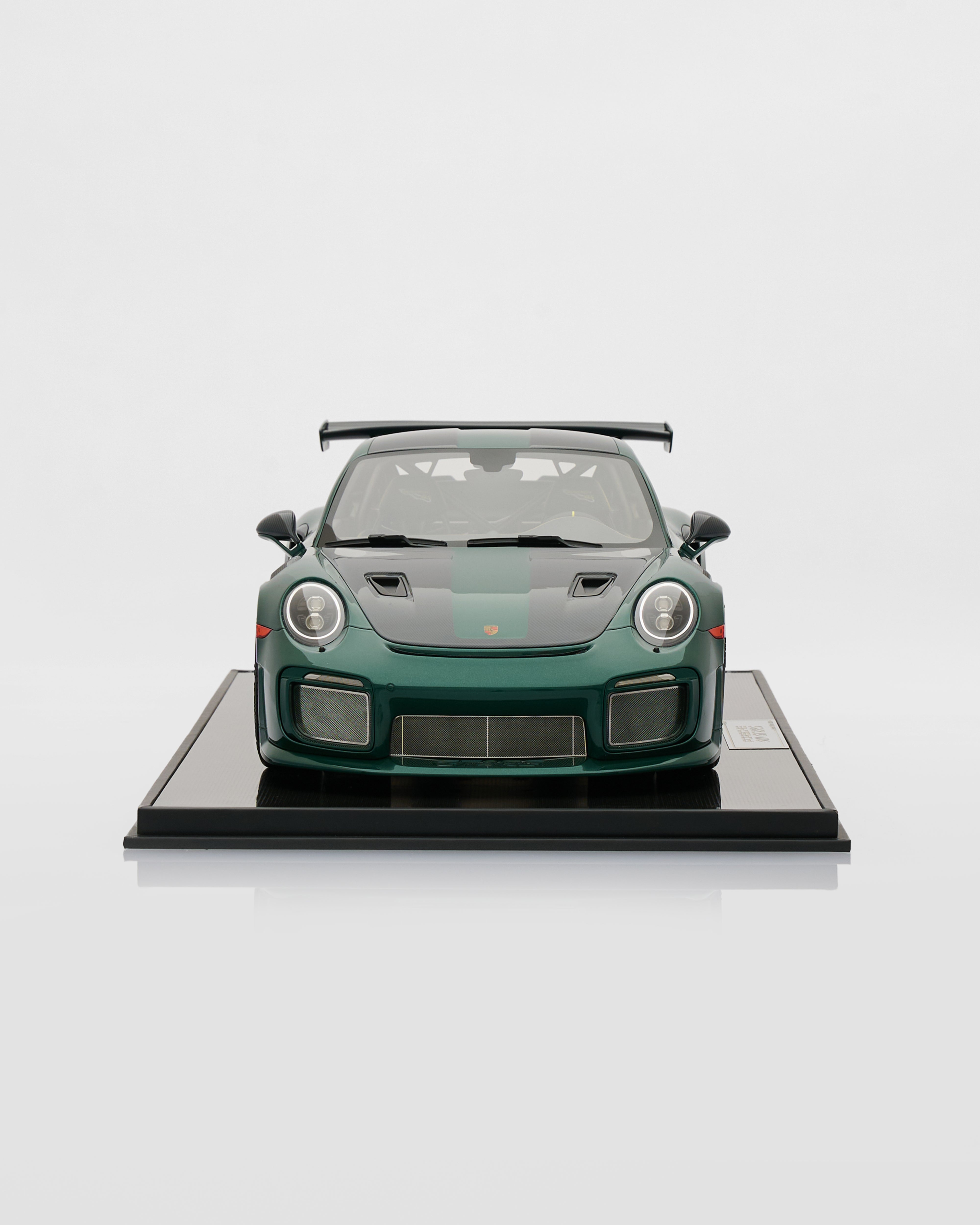Green sports car model on a display stand with a white background