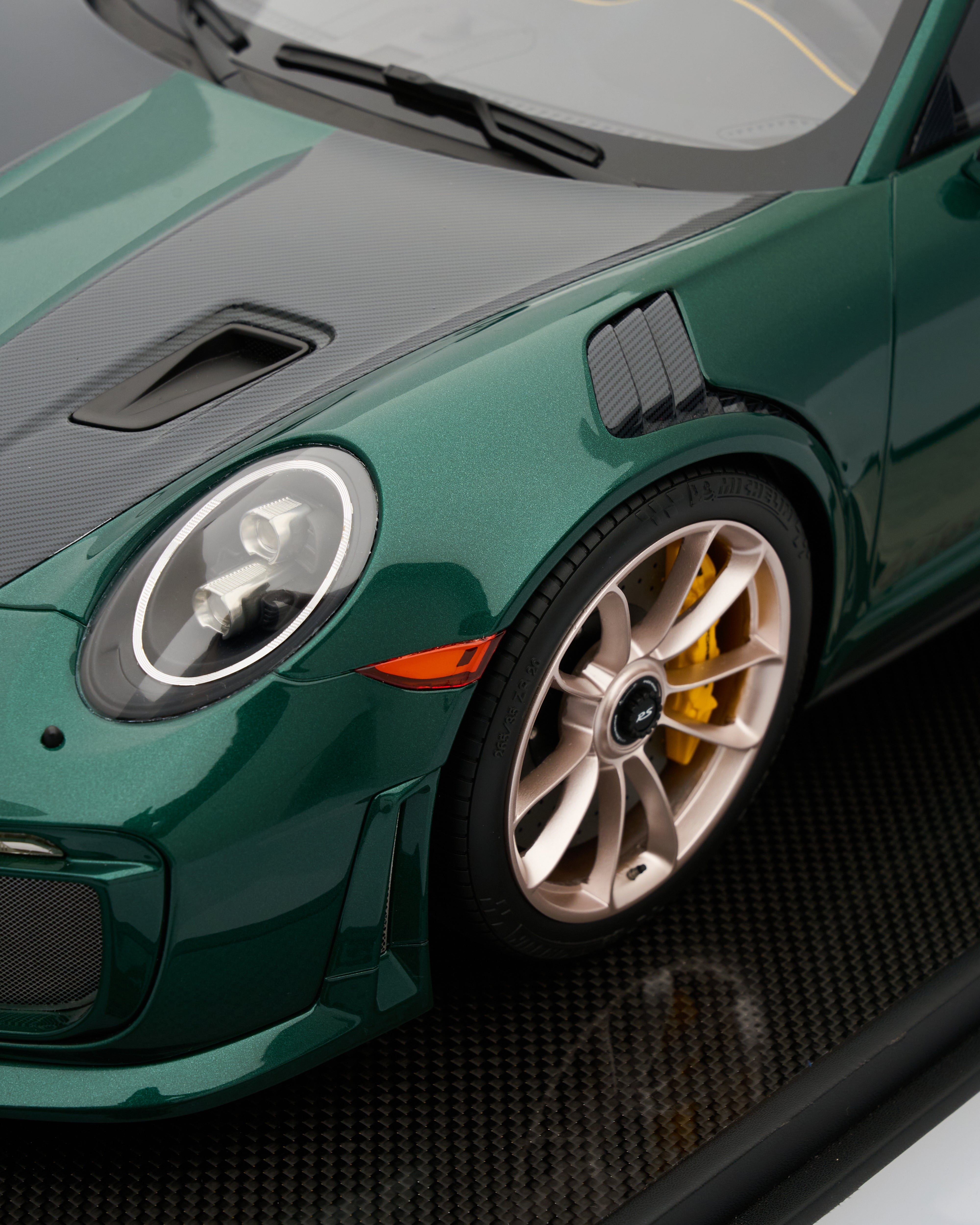 Close-up of a green sports car with a detailed view of the front wheel and headlight.