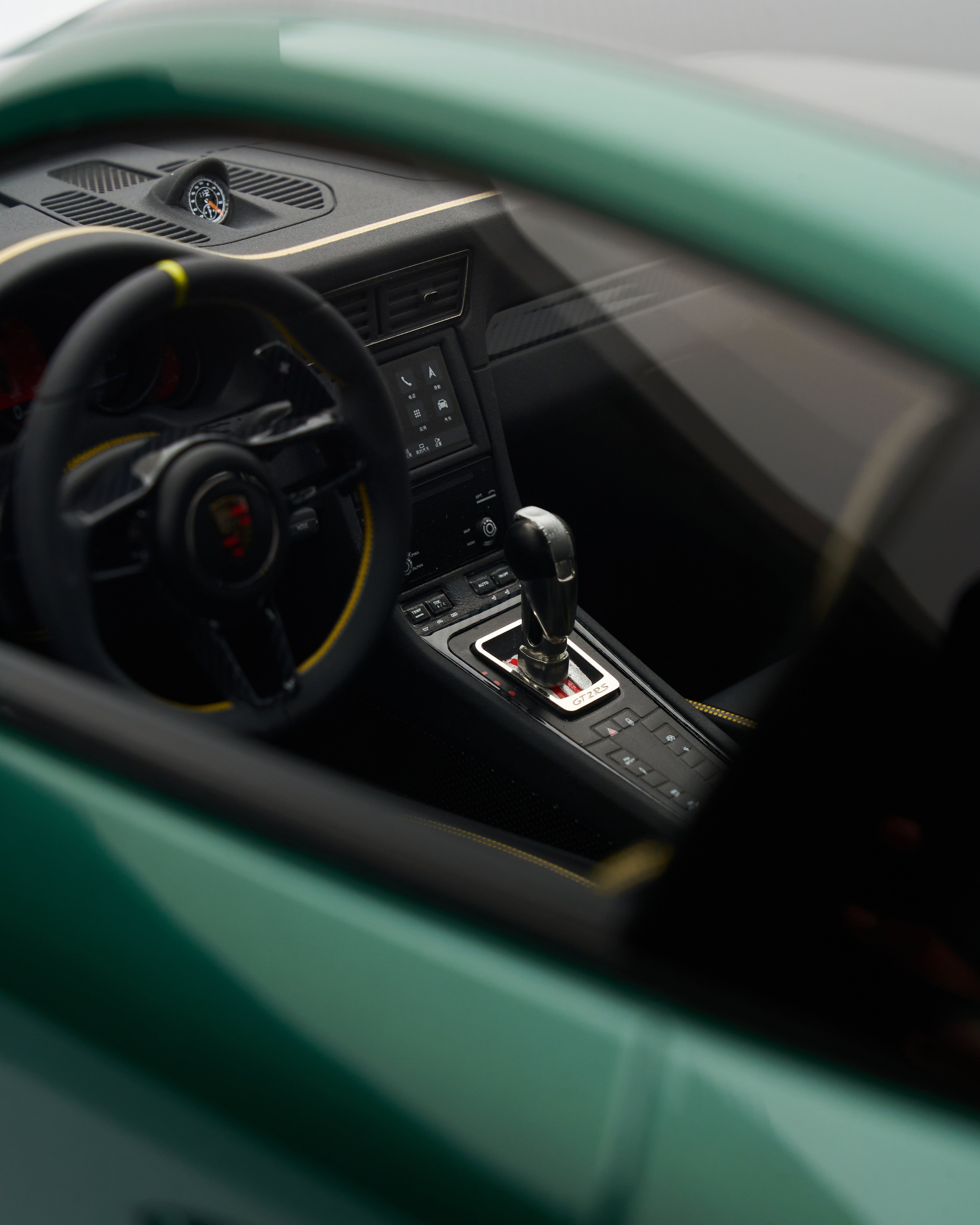 Close-up of a Porsche 911 GT2RS Irish Green steering wheel and dashboard with a visible brand logo.