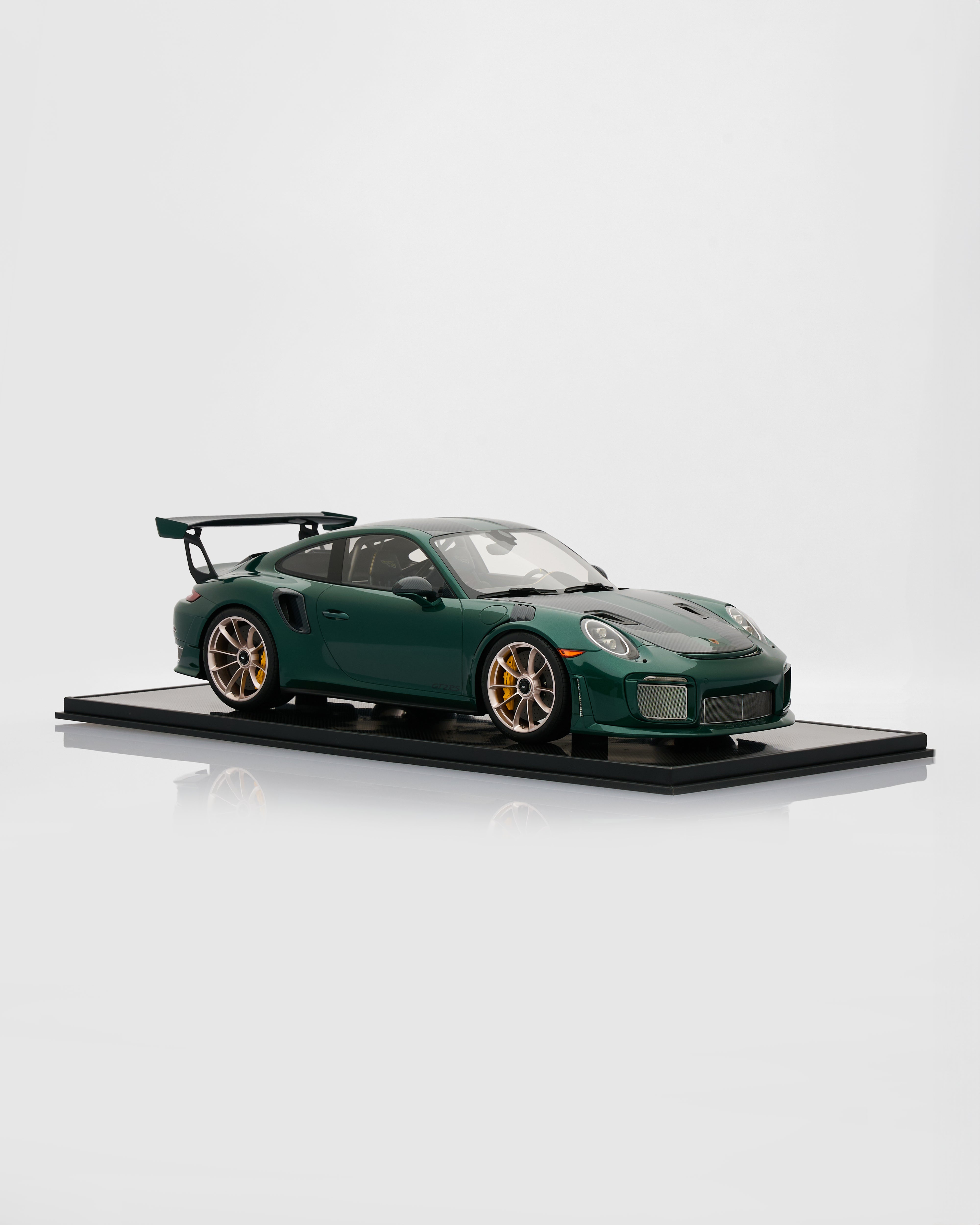 Green sports car model on a black platform with a white background