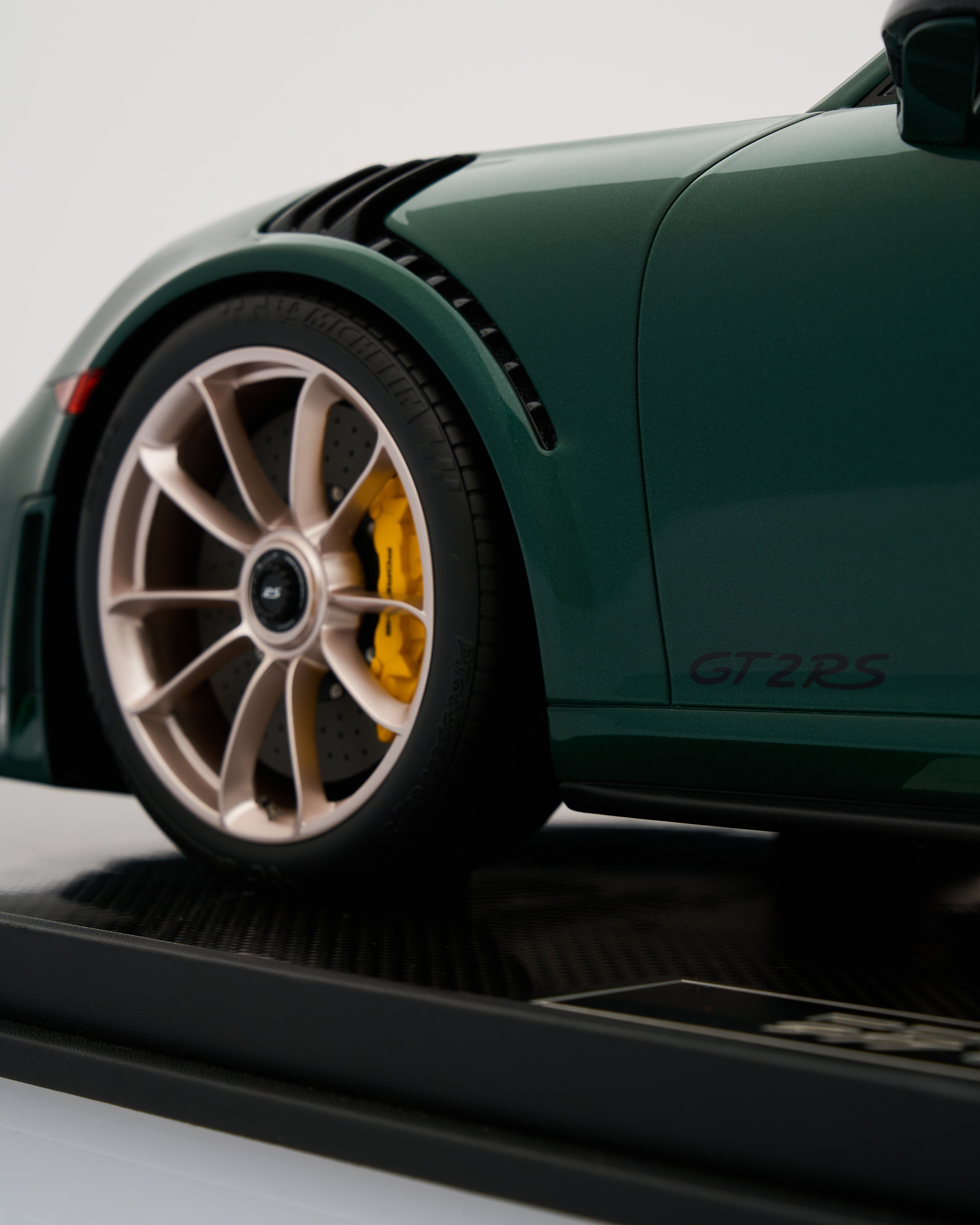 Close-up of a green sports car with a detailed wheel and 'GT RS' branding on a white background.