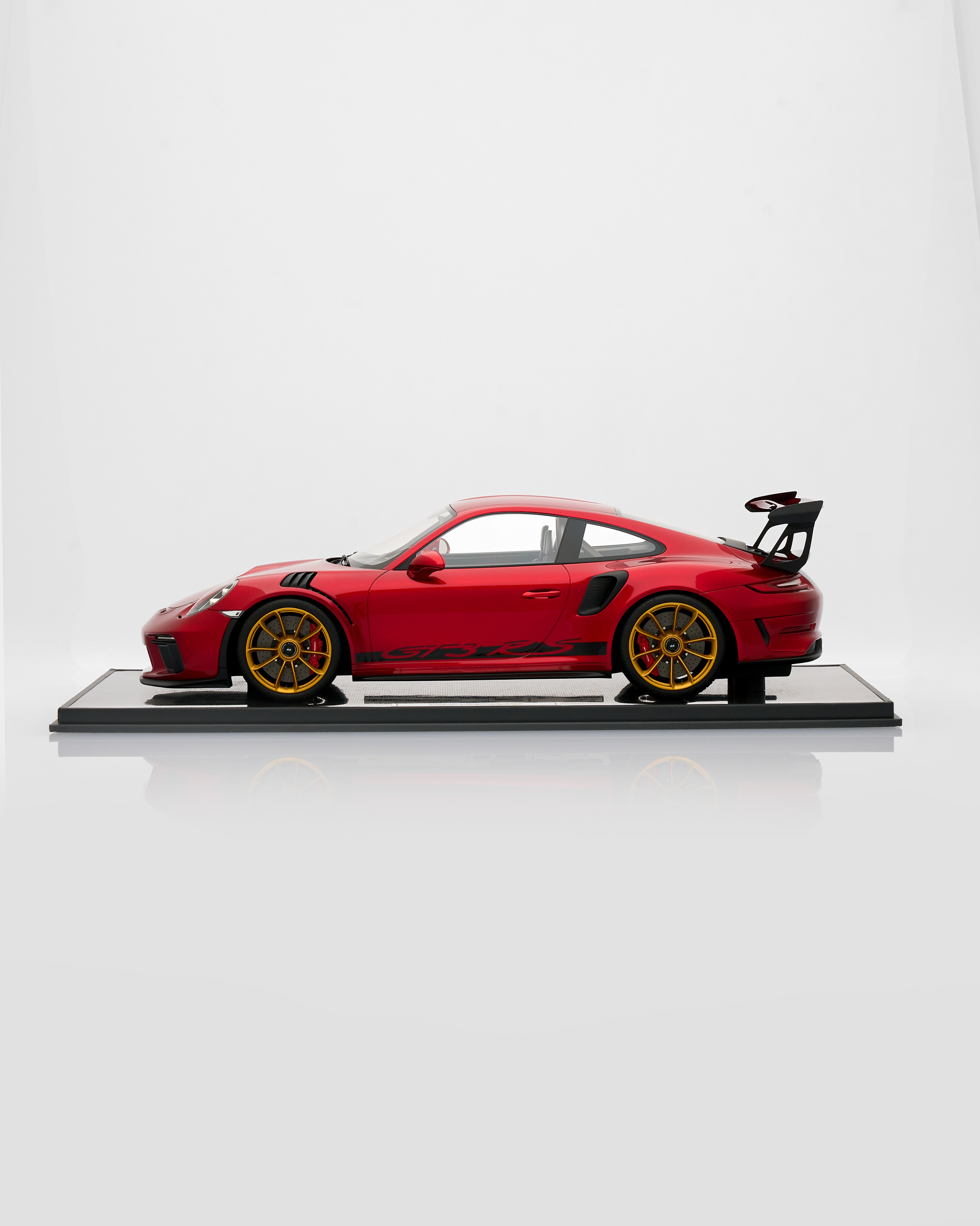 Red Porsche 911 GT3RS Guards Red sports car model on a white platform with a white background