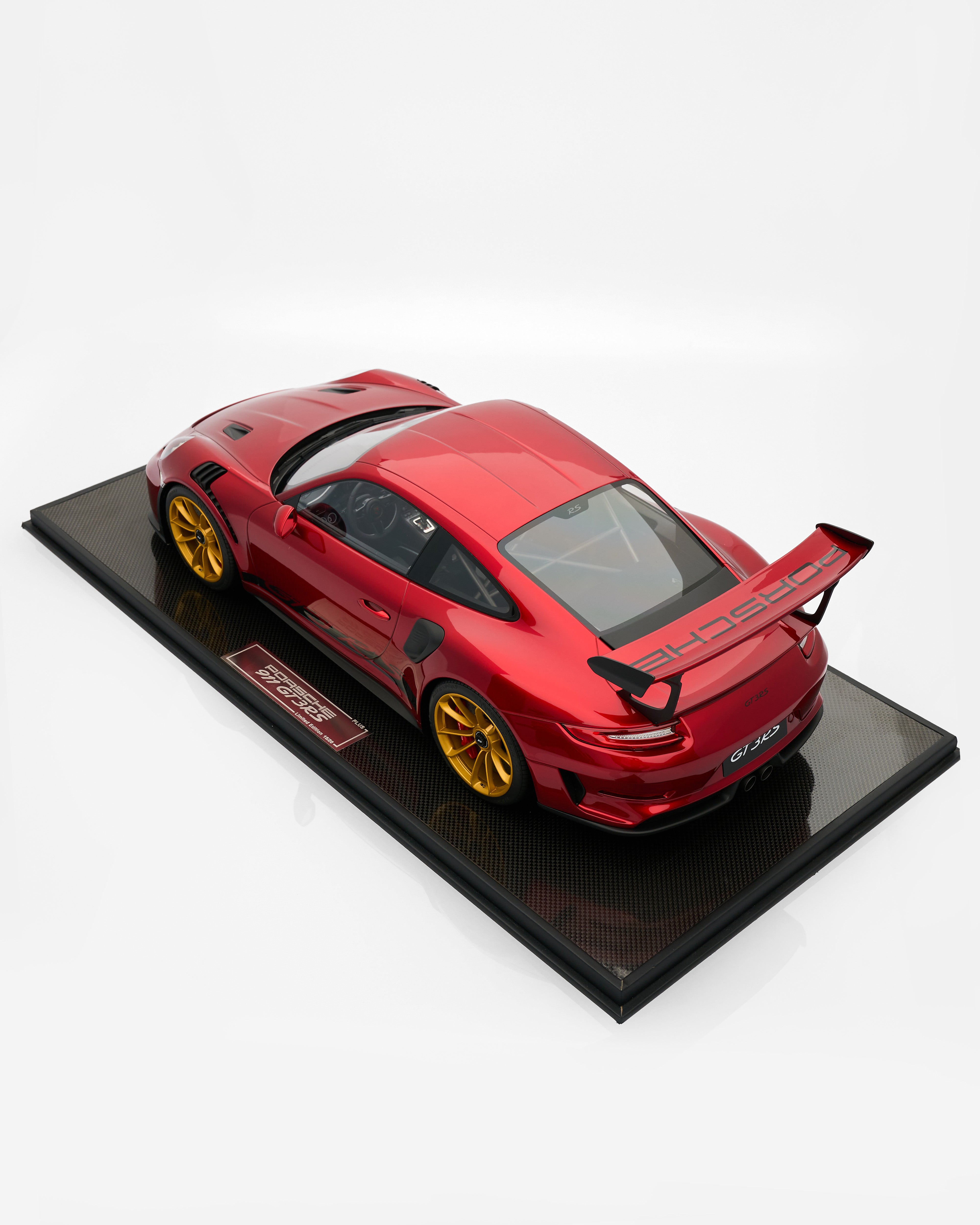 Red sports car model on a black display stand with a white background