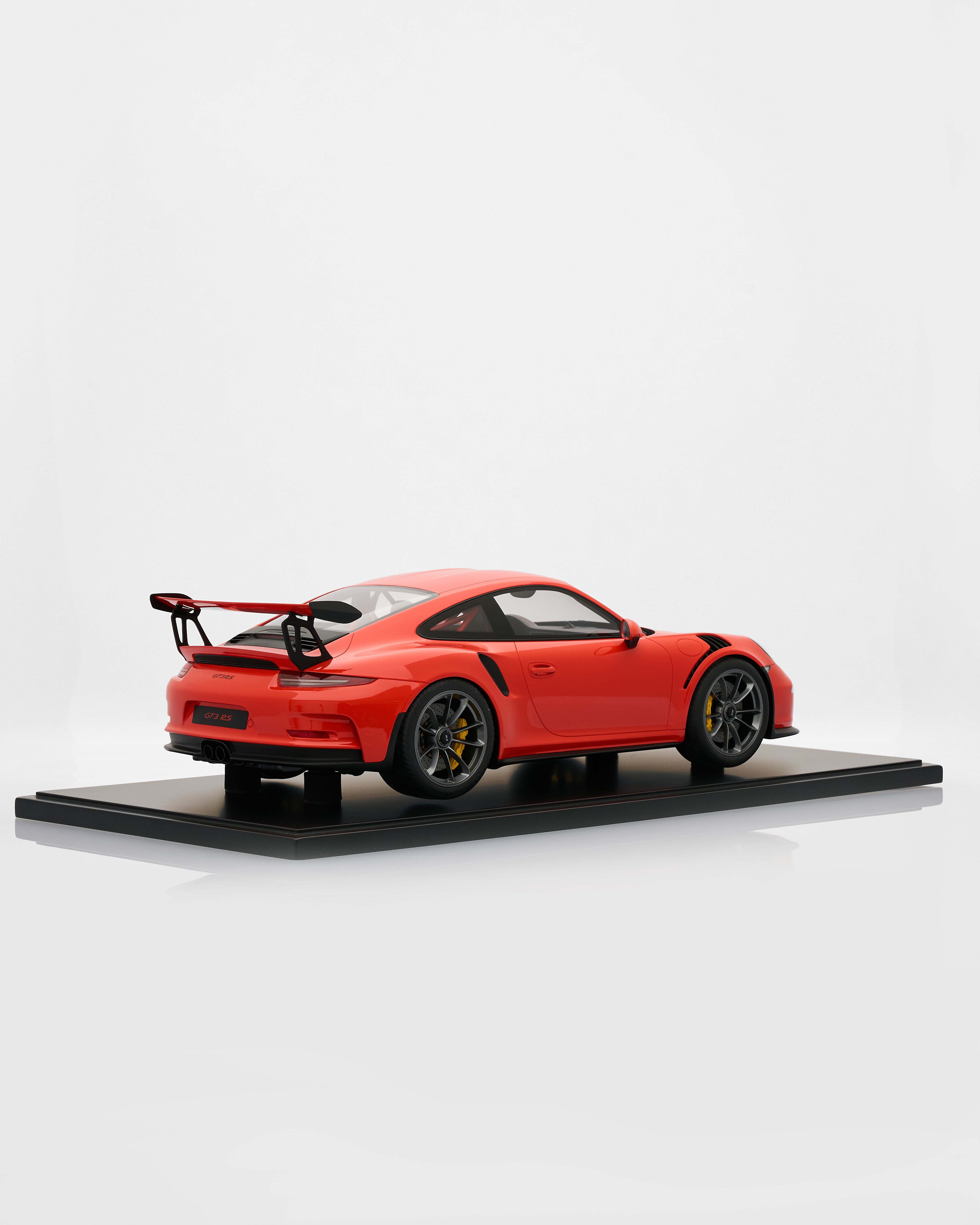 Red Porsche 911 GT3RS Lava Orange sports car model on a black platform with a white background