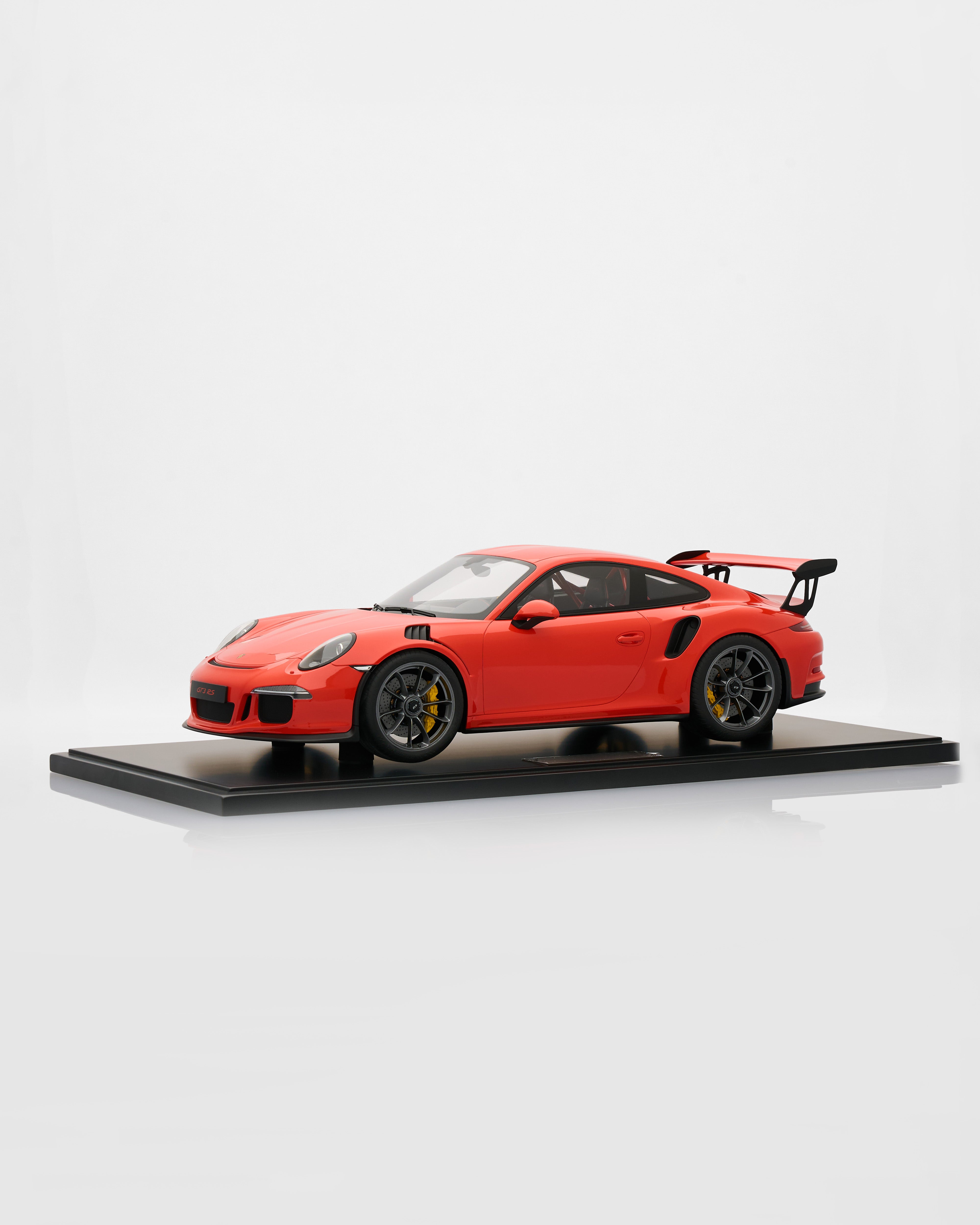 Red Porsche 911 GT3RS Lava Orange sports car model on a black platform with a white background