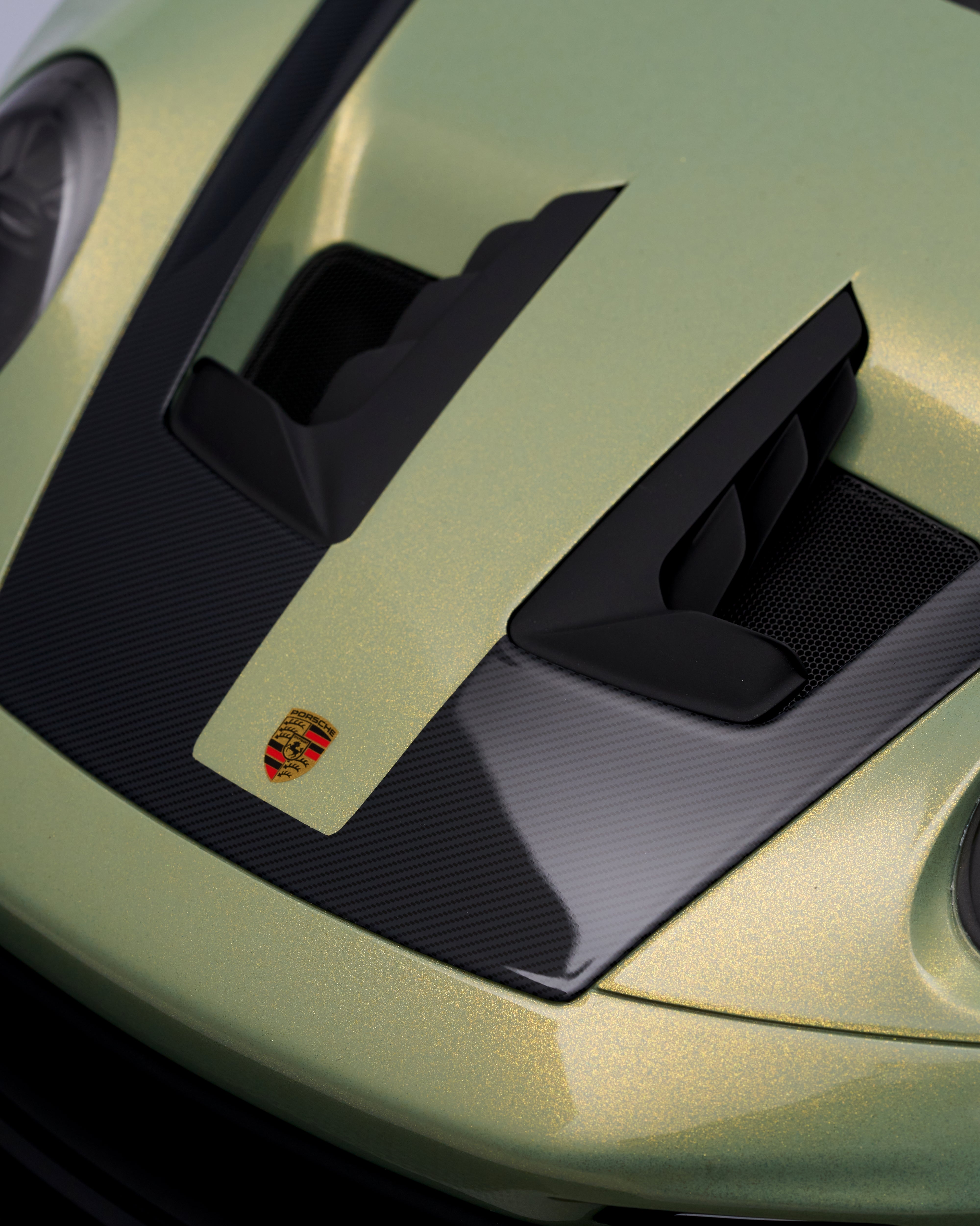 Close-up of a car's air intake with a brand logo on a green background