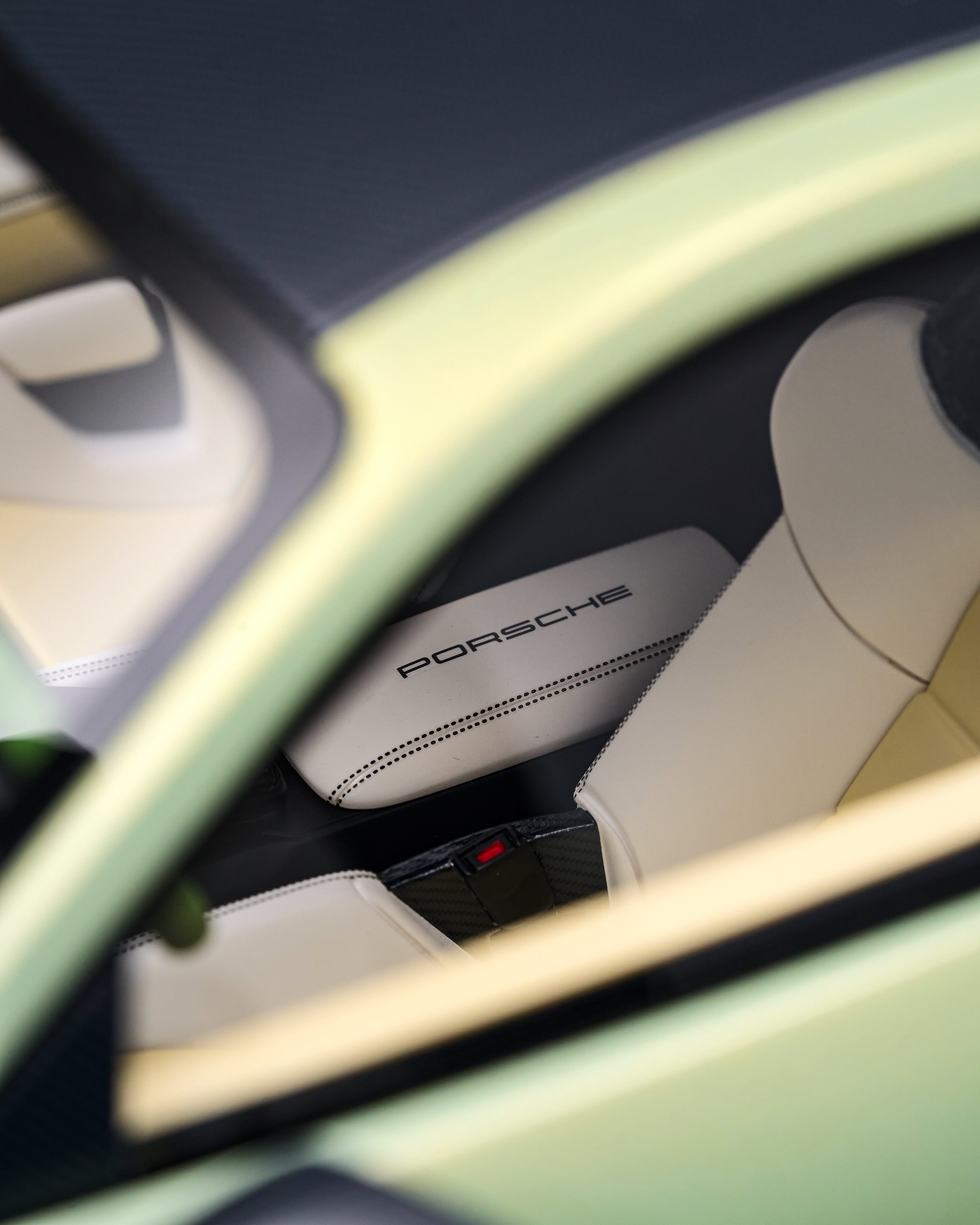 Close-up of a Porsche car interior with white seats and visible branding.