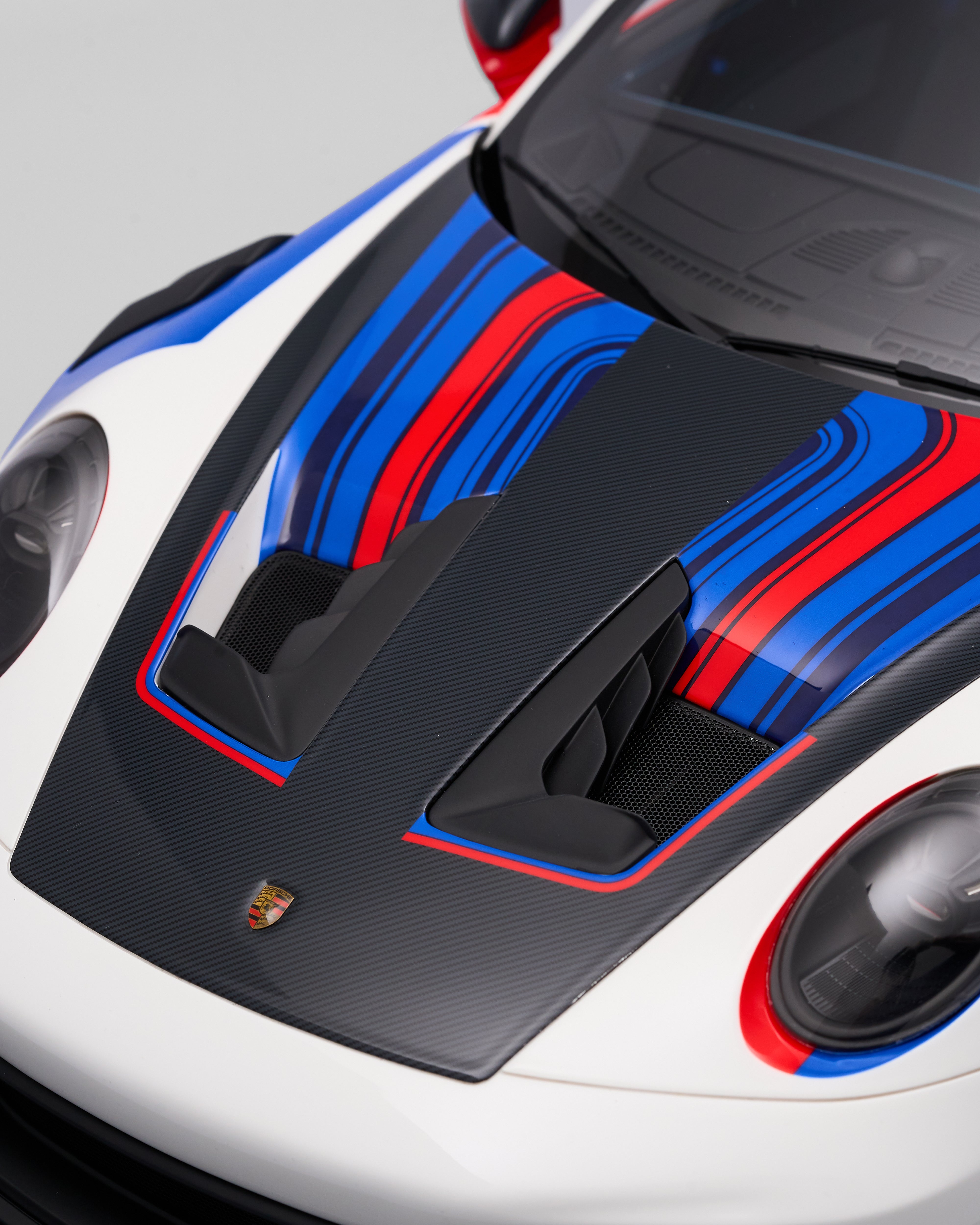 Close-up of a car's hood with a colorful design and Porsche logo.