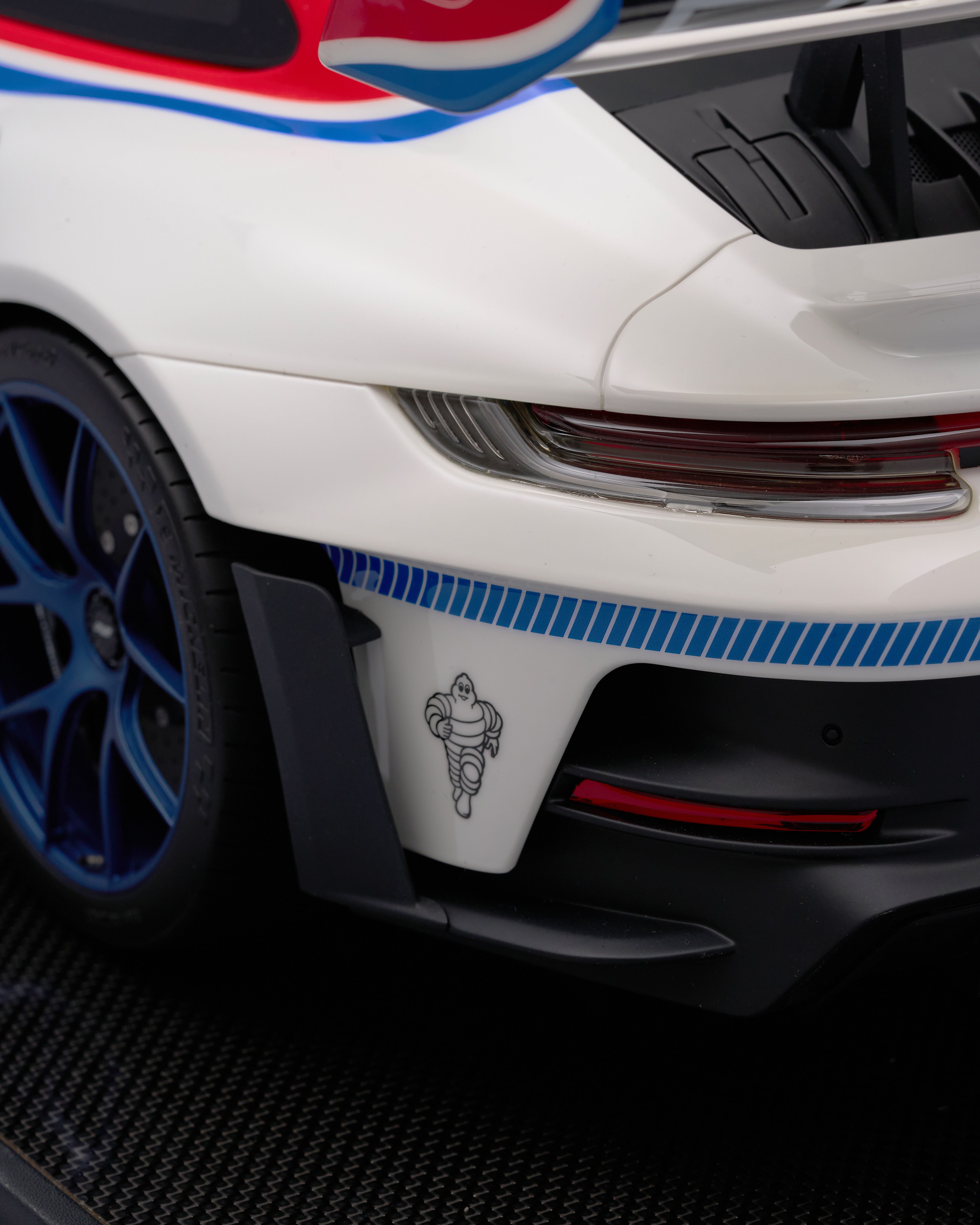 Close-up of a white car with blue and red stripes, featuring a Michelin logo.