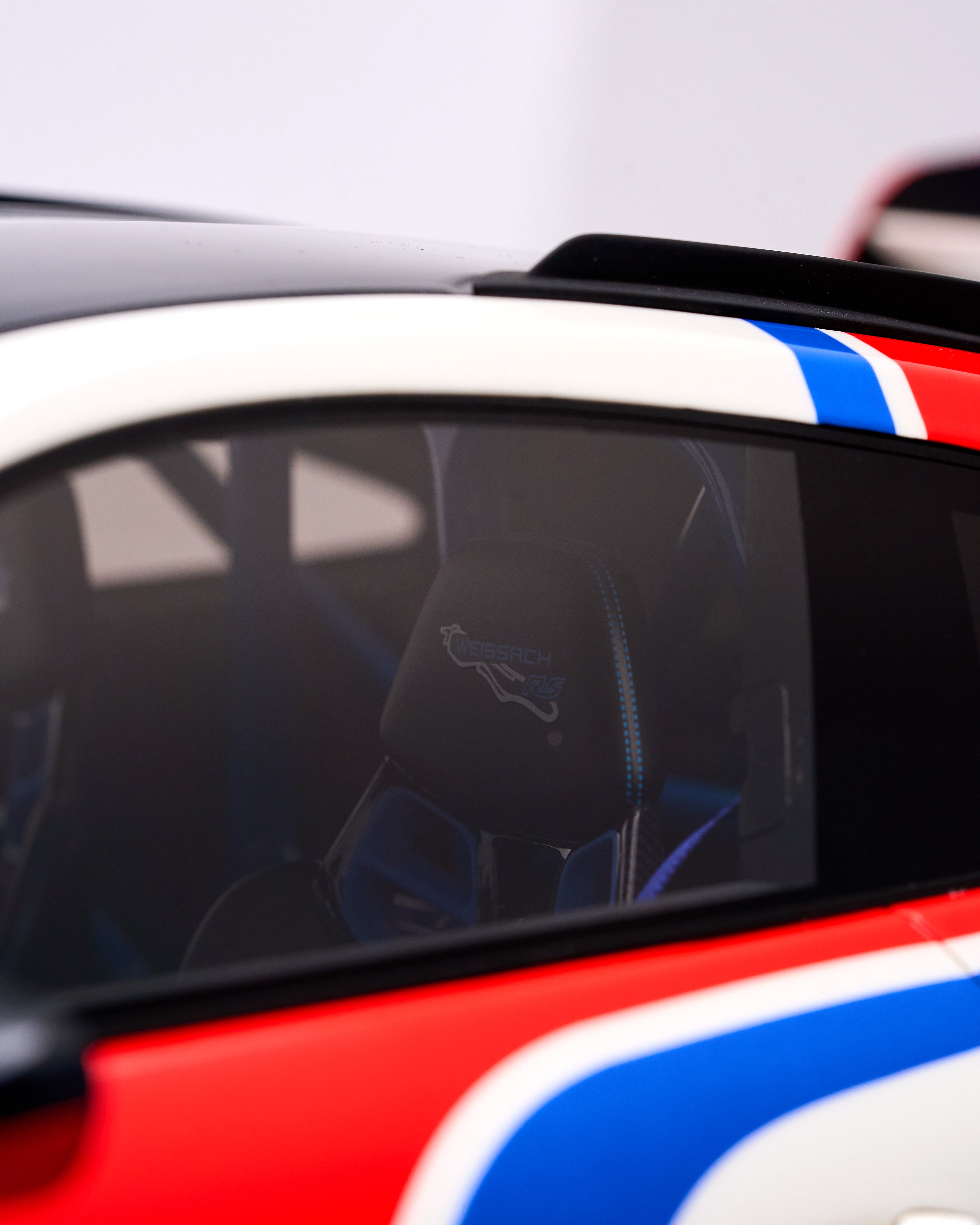 Close-up of a car's rear window with a reflection of a person wearing a helmet.