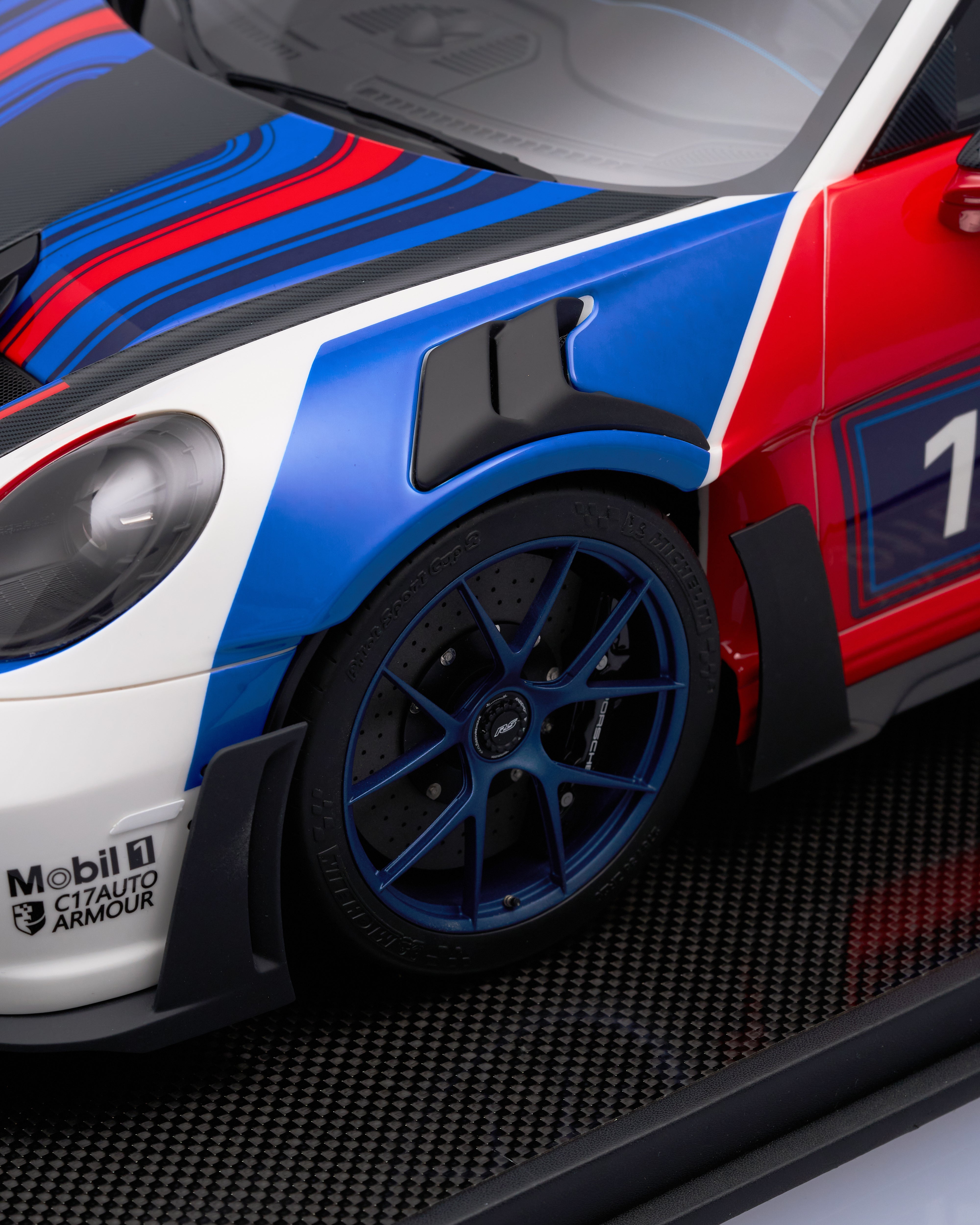 Close-up of a red, white, and blue race car with visible branding on a black background.