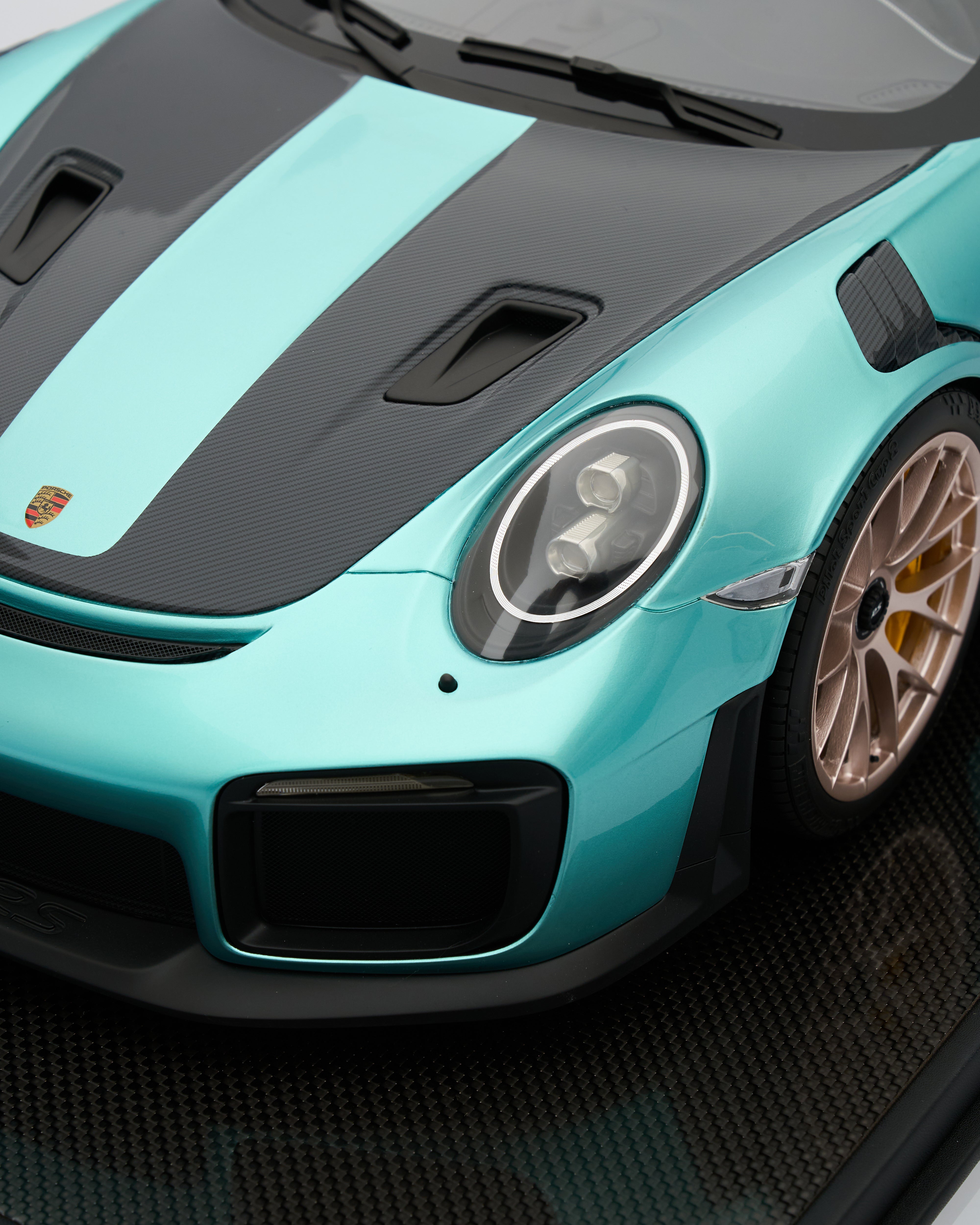 Close-up of a tPorsche_GT2RS_Mint_Green_sports car headlight with a black hood on a dark background