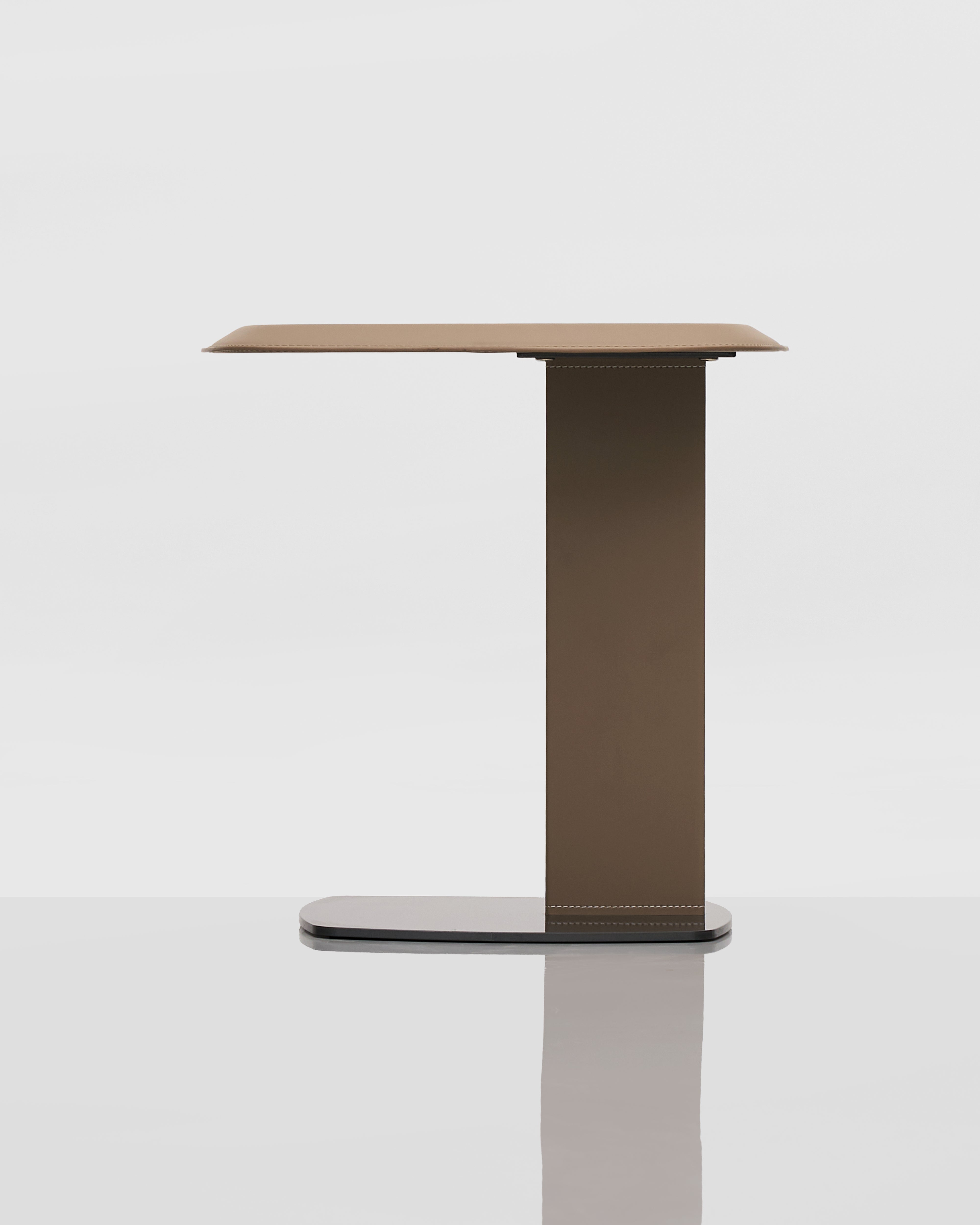Modern side table with a leather covered top and dark metal base on a white background