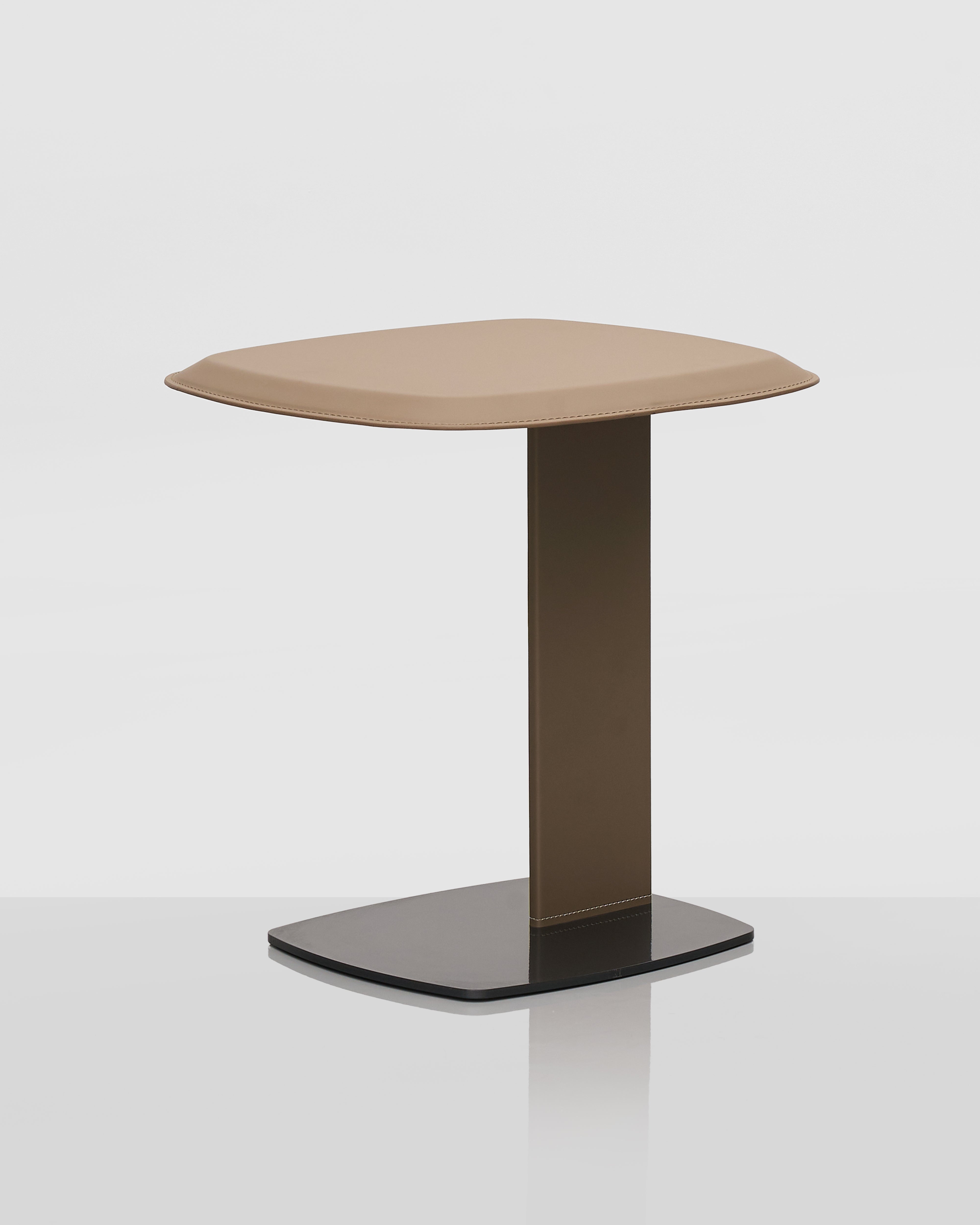 Small side table with a beige top and black base on a white background