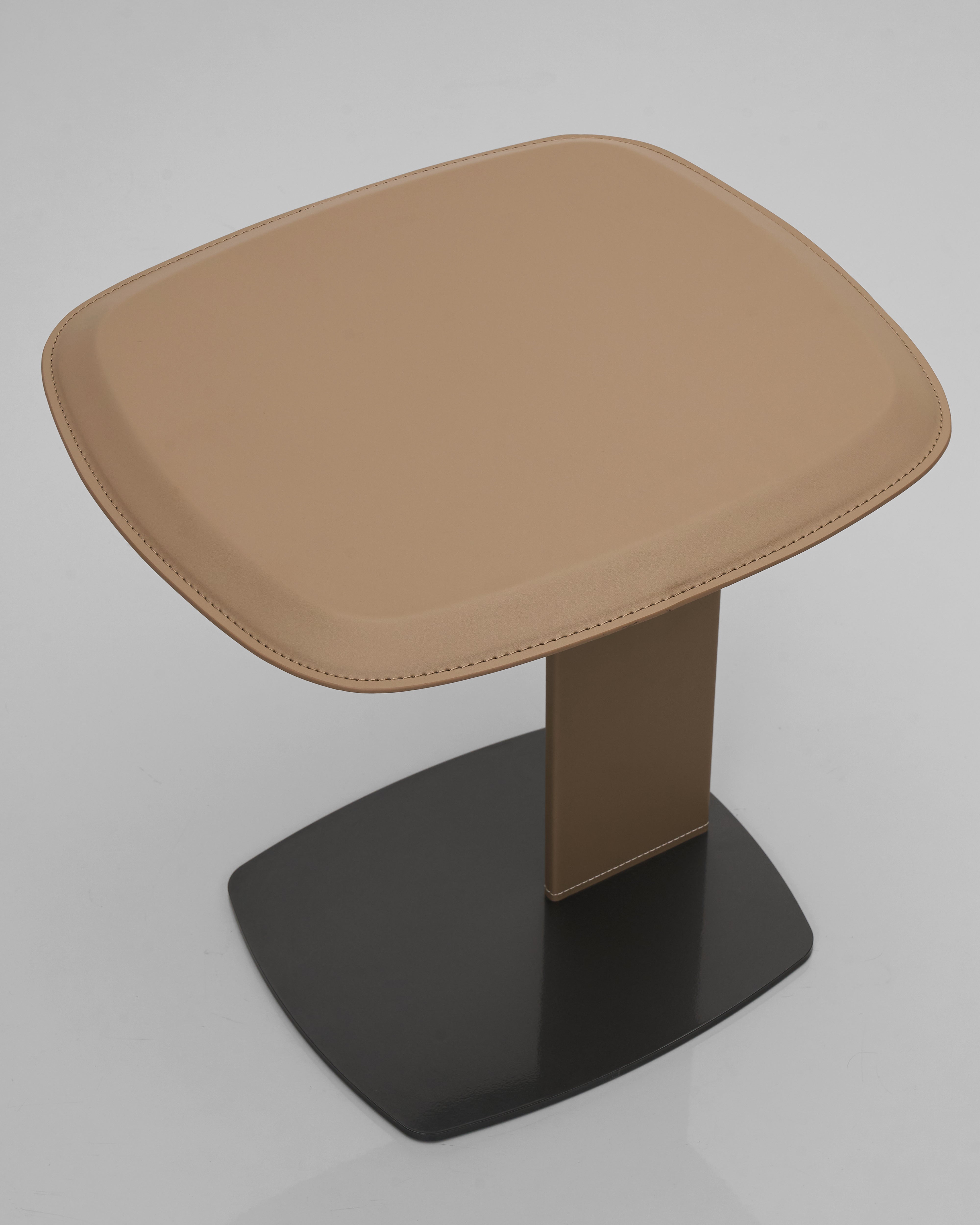 Stool with brown cushioned seat and black base on a gray background