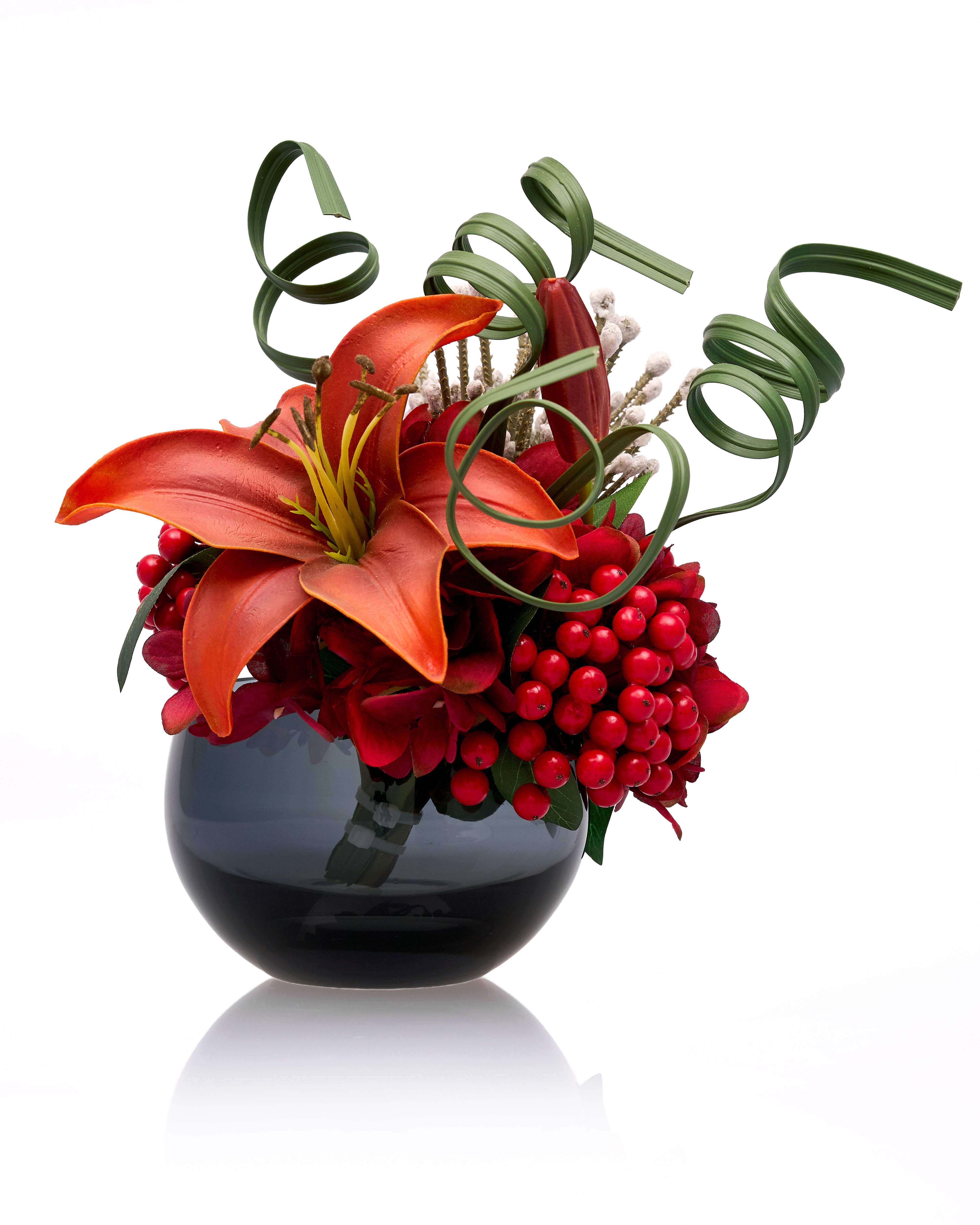 Floral arrangement with red flowers and greenery in a black vase on a white background